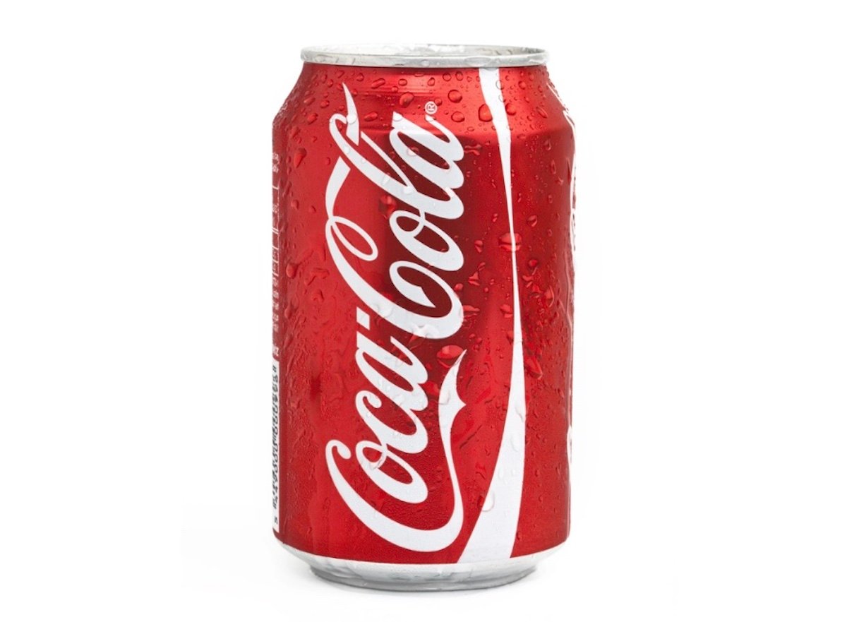 A red can of Coca-Cola with condensation droplets on the surface stands upright against a plain white background. The white Coca-Cola logo is prominently displayed, making it a striking piece for fans of expensive collectibles.