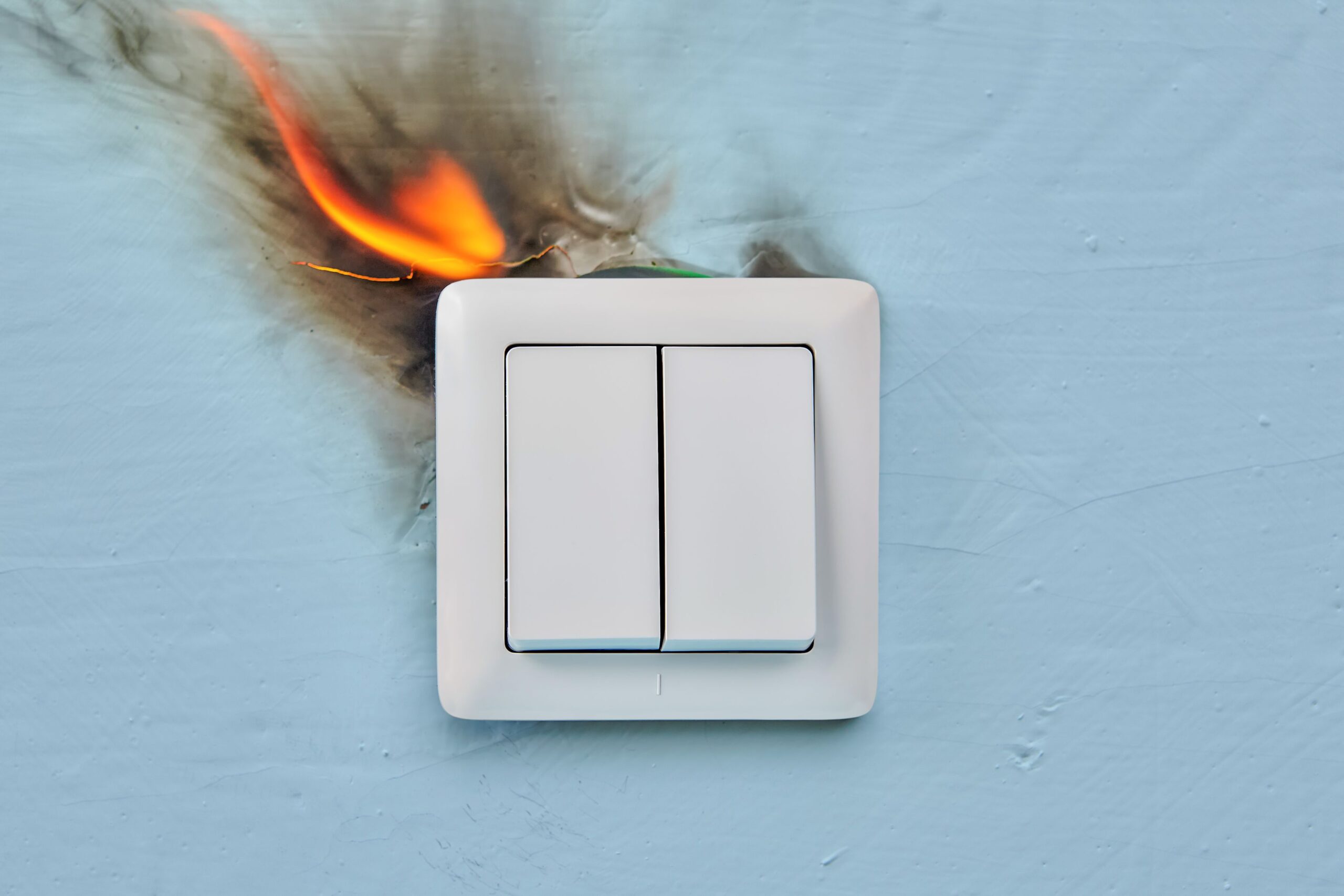 Electrical fire is starting at home due to a faulty wall electric outlet.