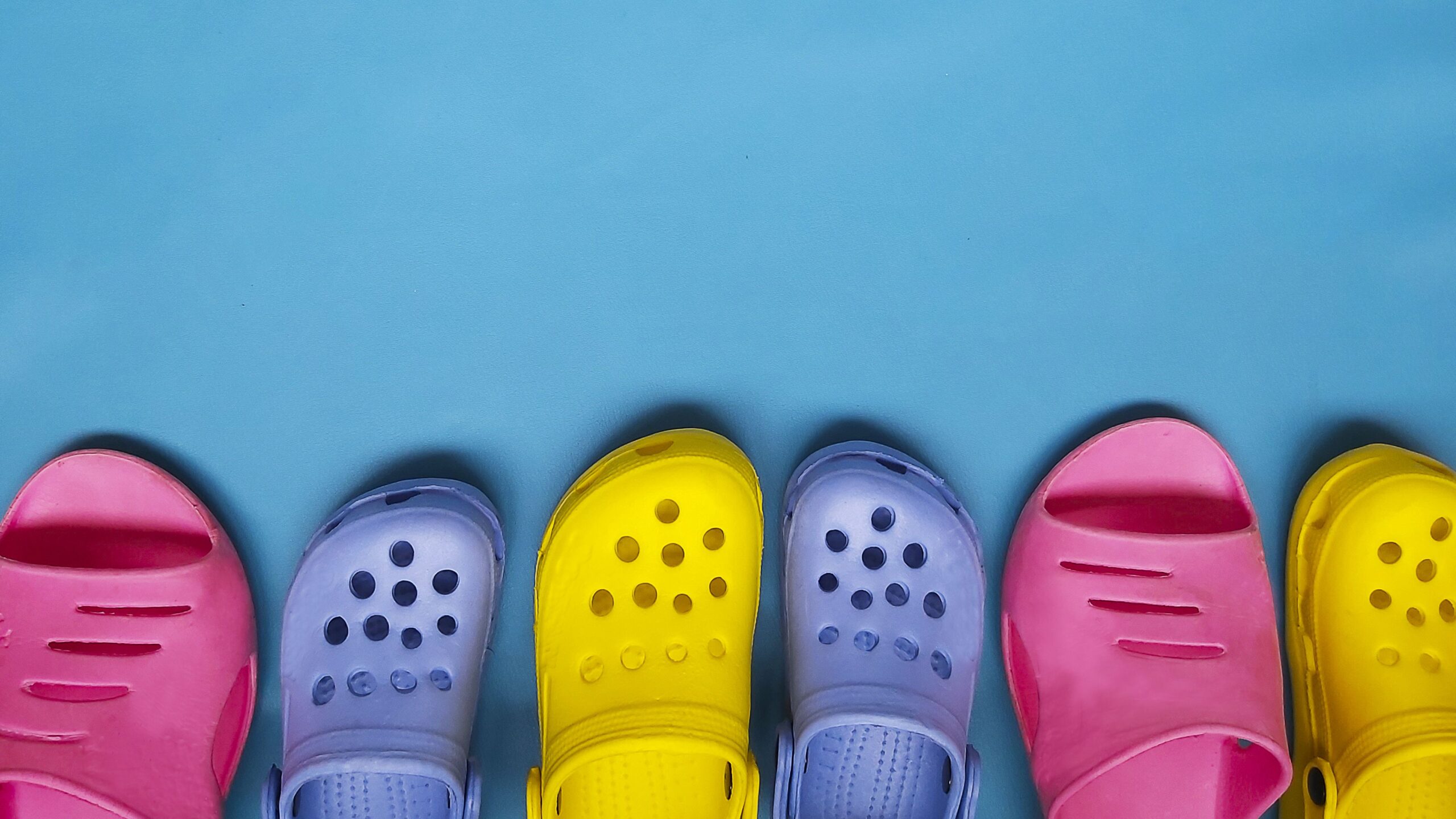 Colored bright slippers for women and children flip flops on a blue background. Place for text.