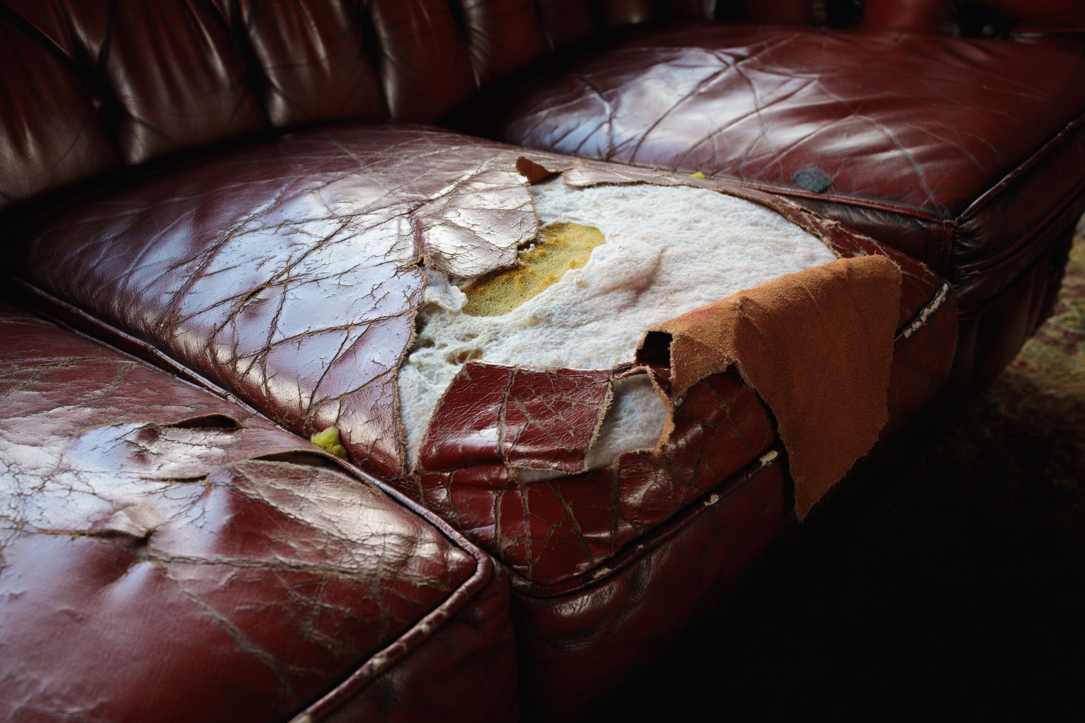 Old dark red leather sofa showing its age.