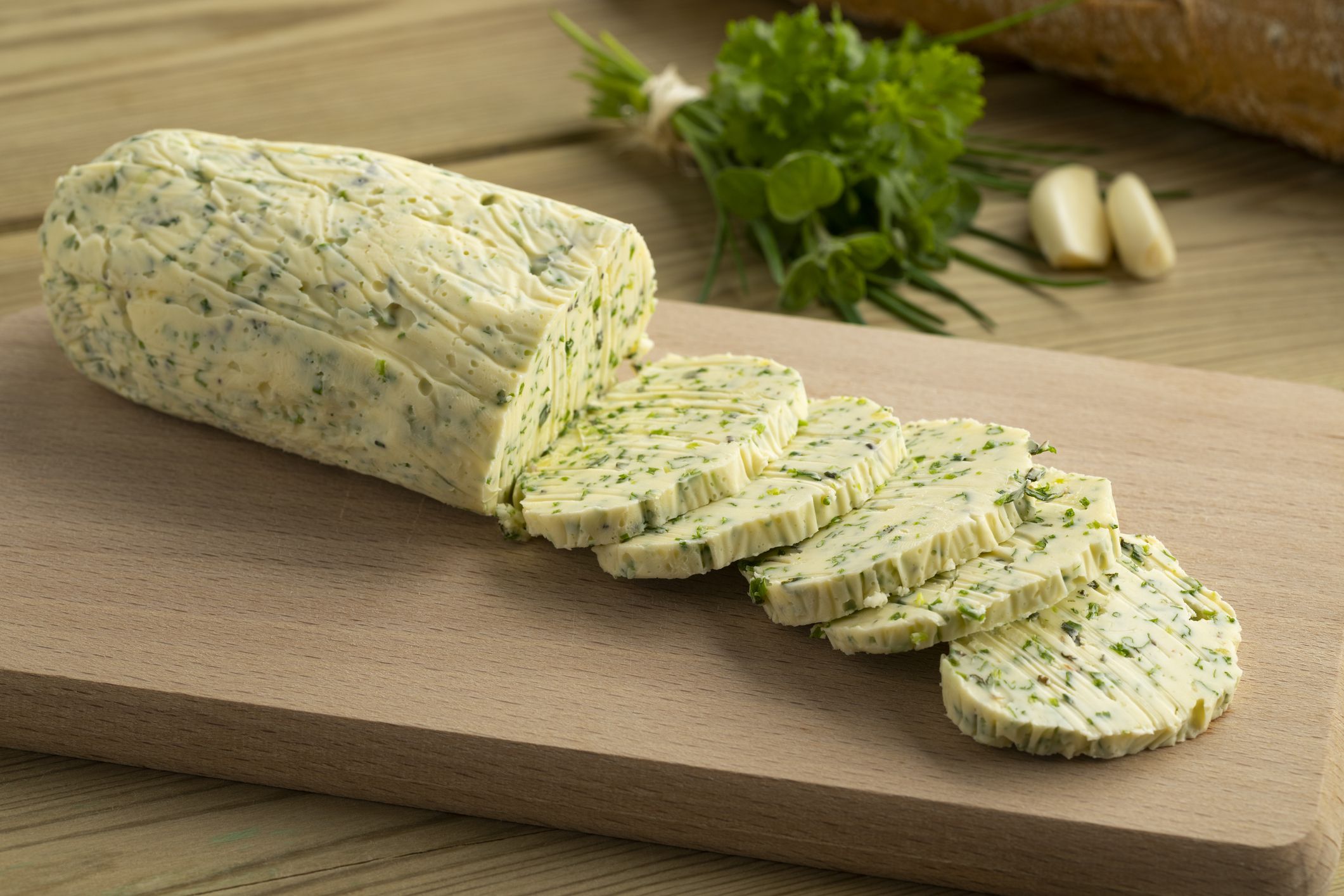 Sliced fresh made herb butter close up on a cutting board