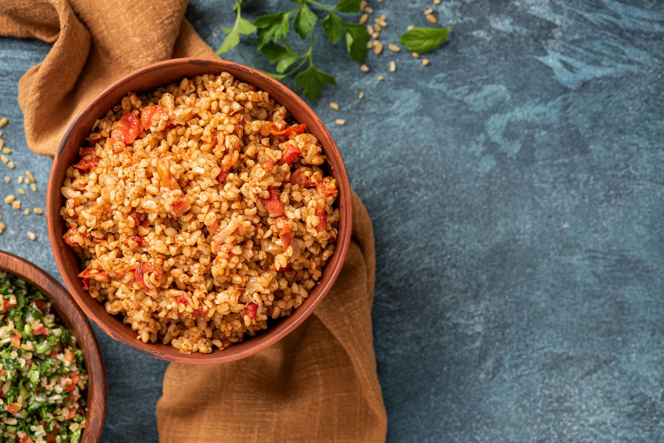 Easy bulgur pilaf (pilavi) with tomatoes in a ceramic bowl on a dark background top view. Turkish cuisine, vegan food.