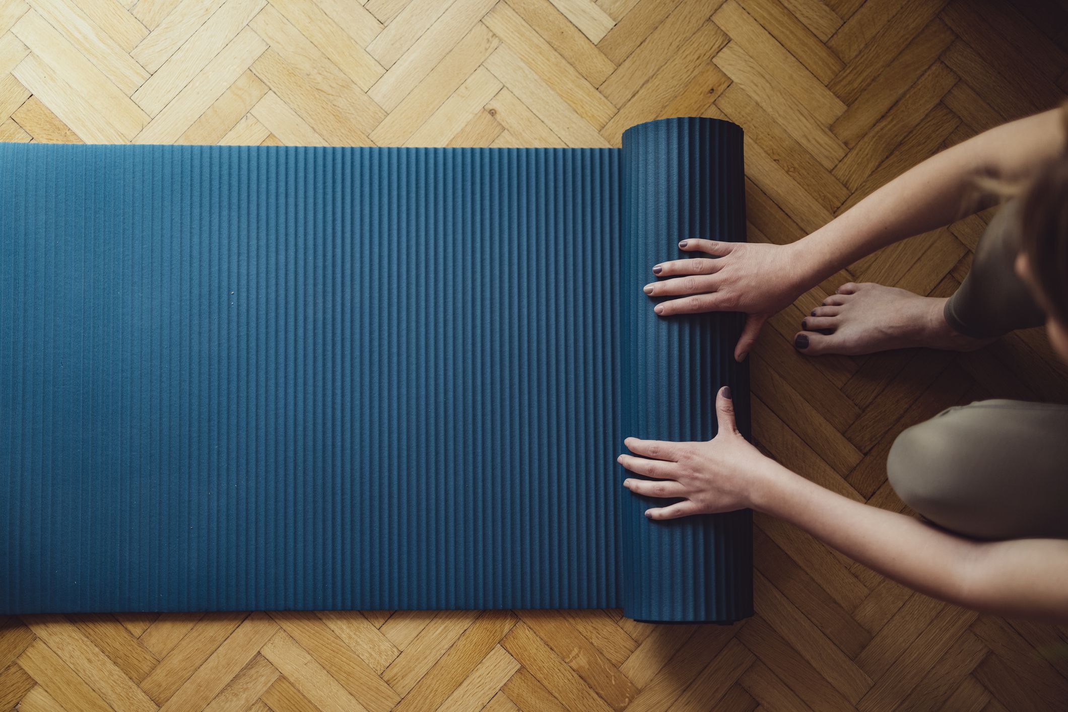Top view of woman folding fitness mat before or after working out at home