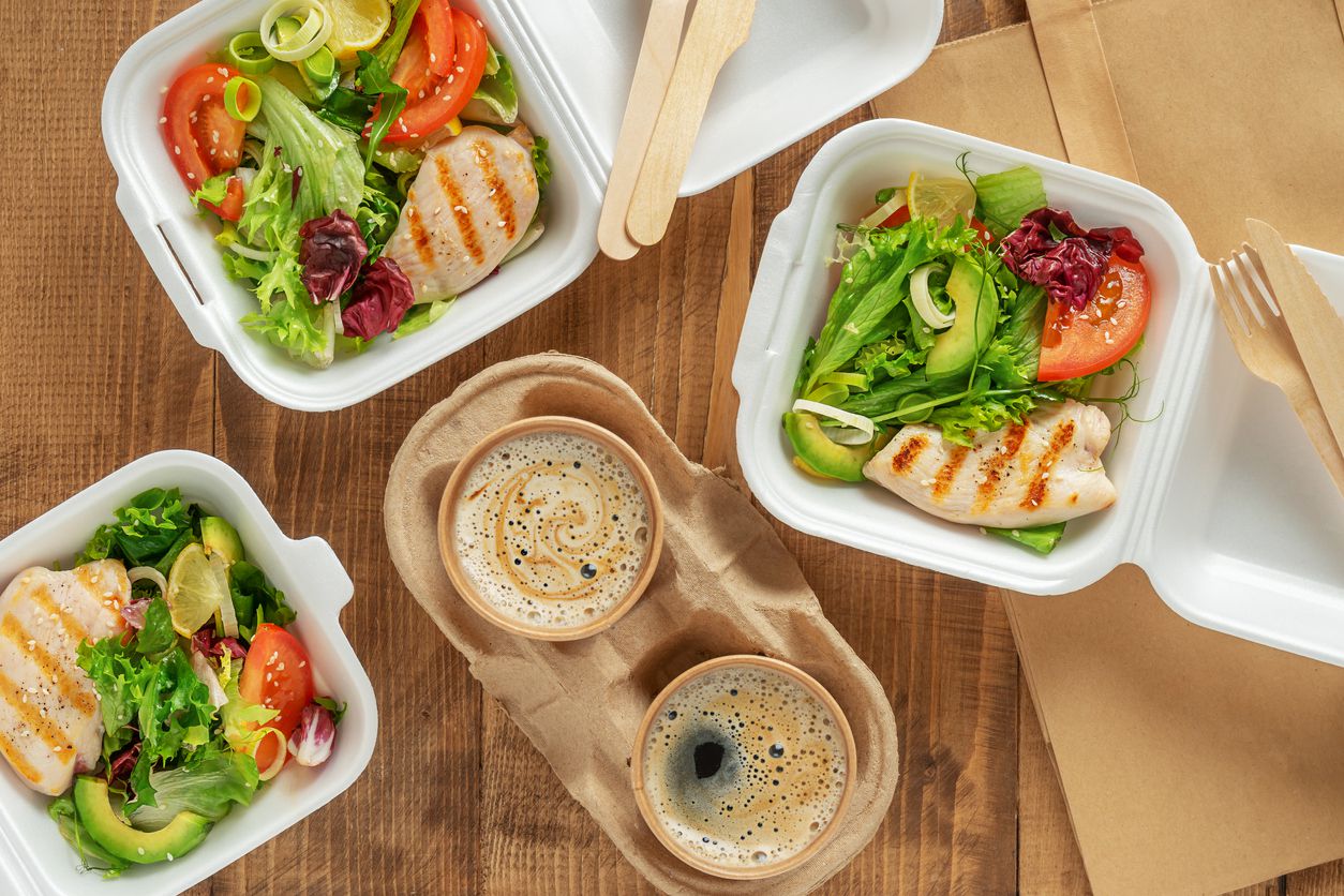 A takeaway lunch that includes a fresh salad and grilled chicken.