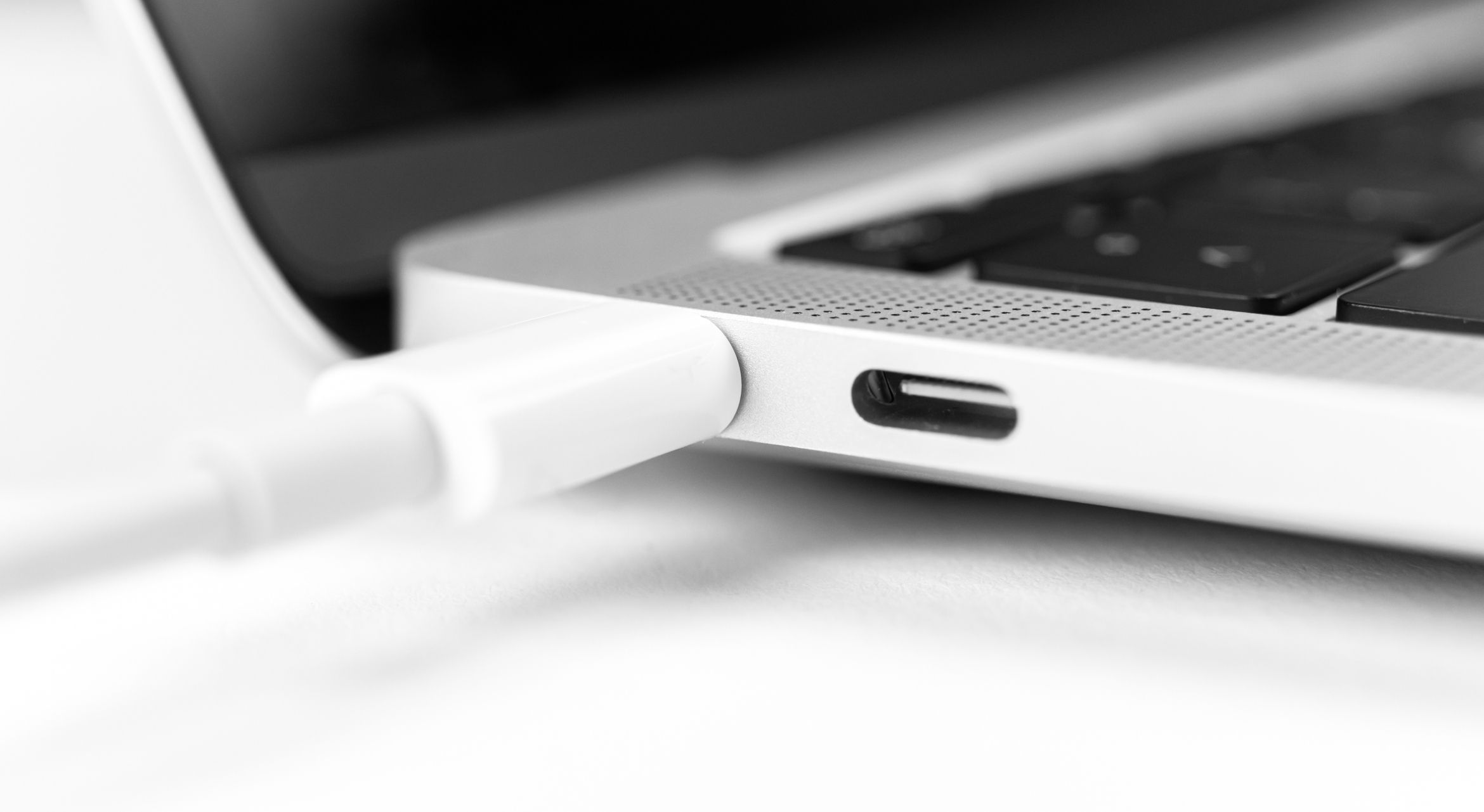 Charging battery laptop. Modern USB C port for fast charge. White cable plugged in laptop close-up view