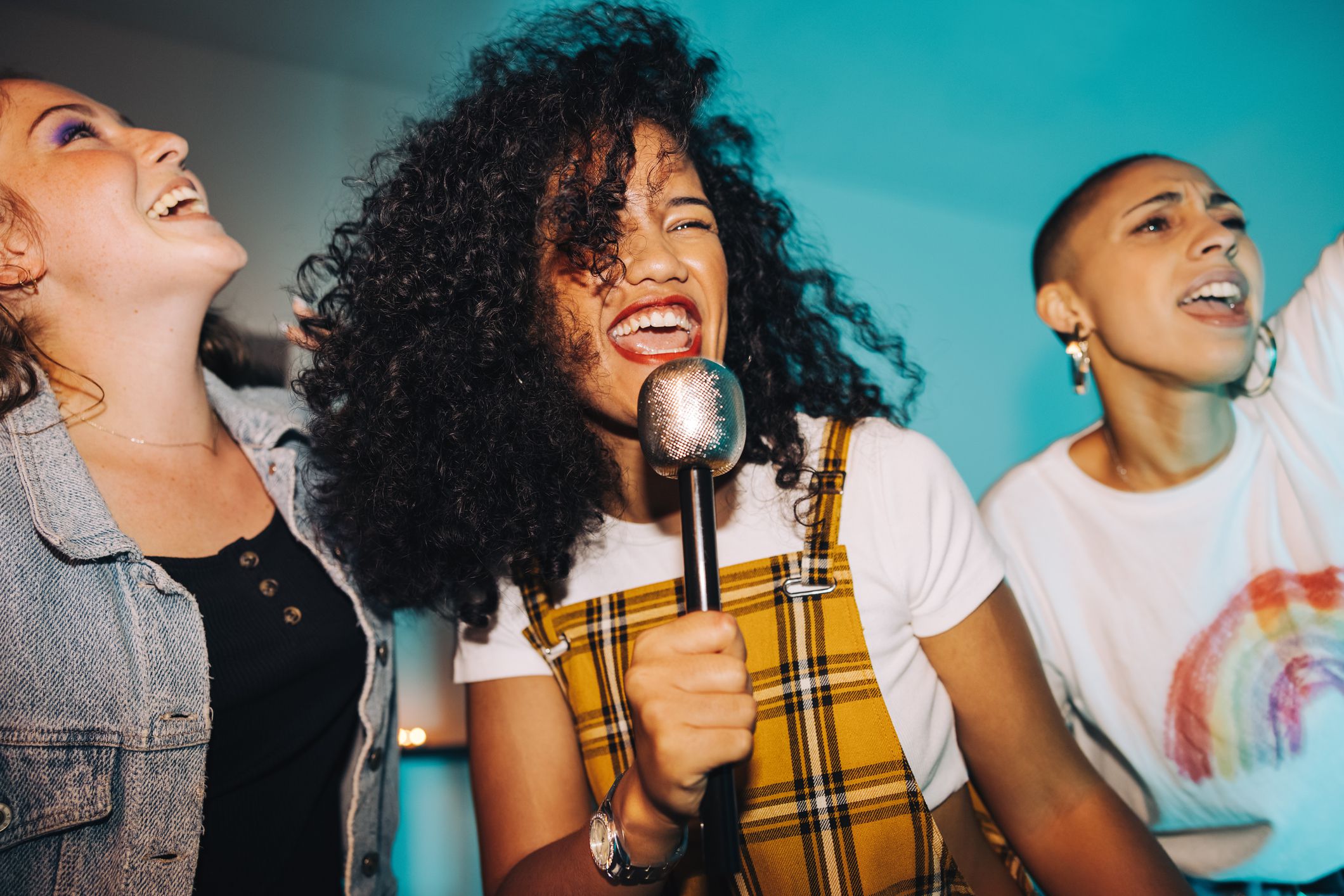 Karaoke time. Vibrant young woman singing into a microphone while partying with her friends at night. Group of happy female friends having a good time together on the weekend.