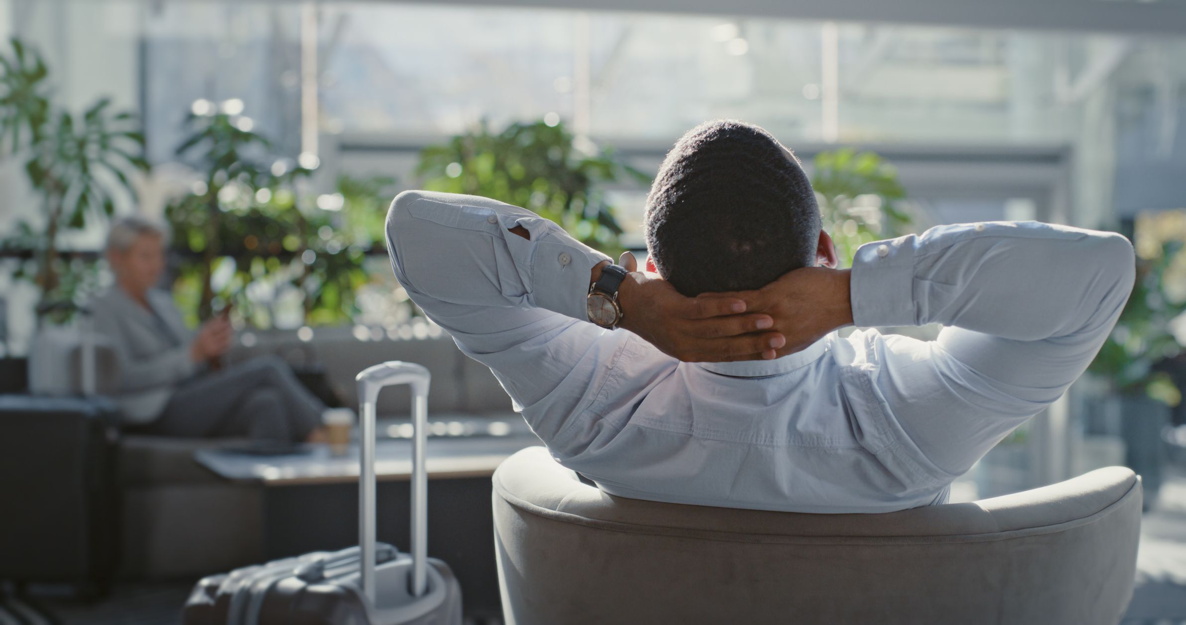 Travel, airport and businessman relax in lounge before airplane flight for company, corporate or executive job work. Calm mindset, luggage and back view of ceo sleeping in hotel lobby before journey