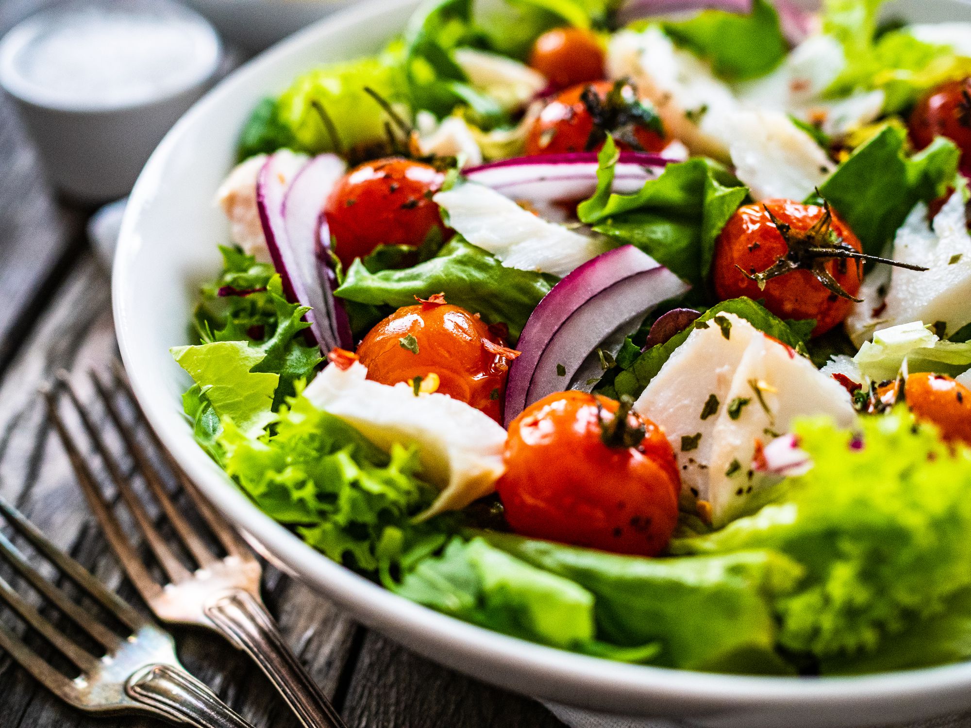 Roast cod and vegetable salad on wooden background