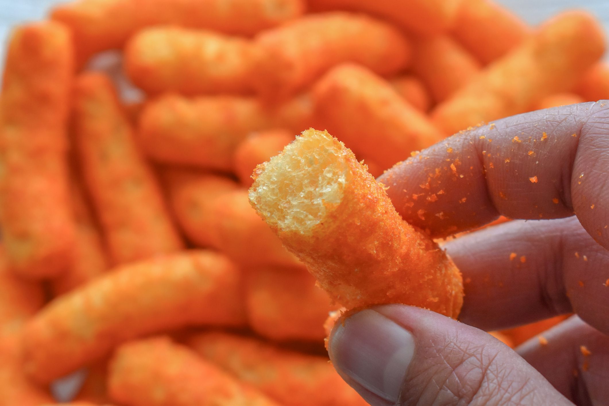 Spicy crunchy corn snack in hand. High sodium food.