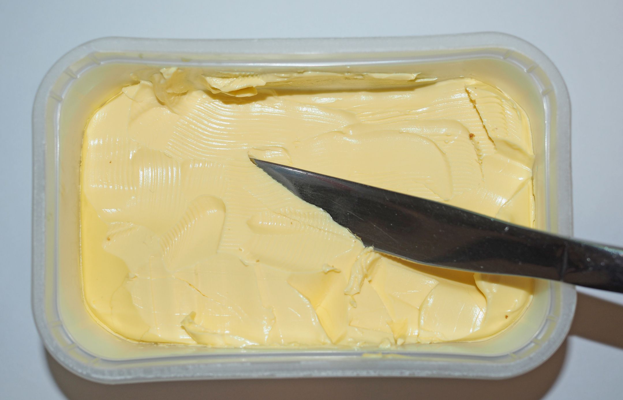 Knife in a tub of yellow butter in kitchen