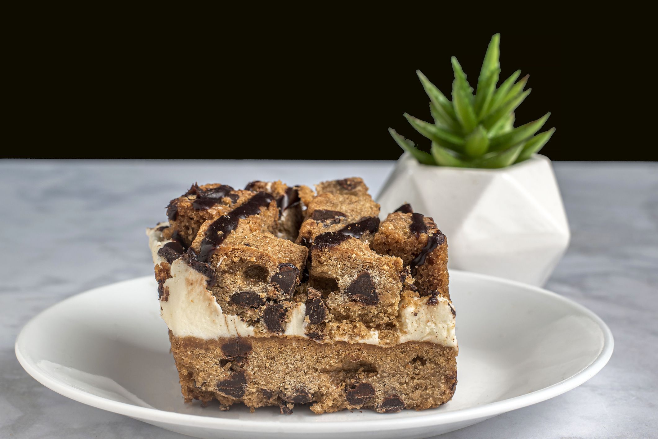 chocolate chip cookie square filled with whip cream on a plate
