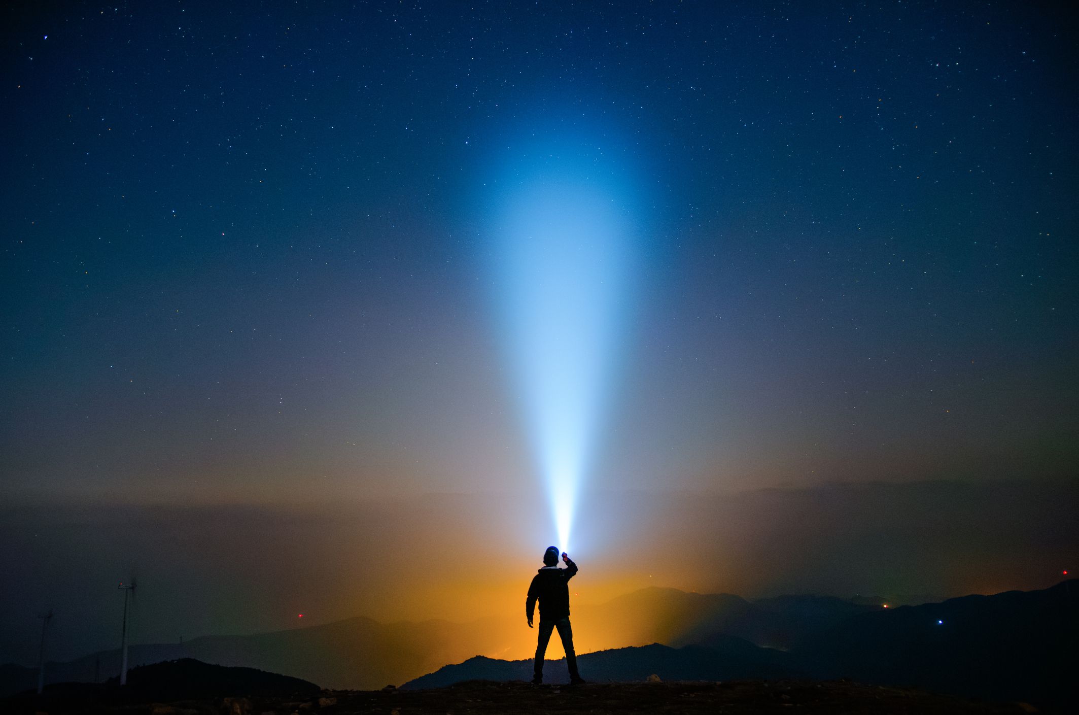 A person holding a flashlight under the starry sky
