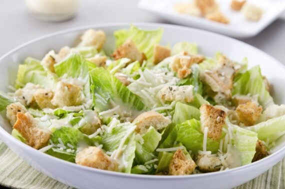 SEVERAL MORE IN THIS SERIES. Closeup of a fresh caesar salad, with romaine lettuce hearts, croutons, parmesan cheese and dressing. Dressing and croutons in background. Very shallow DOF. Foods that reveal a good restaurant.