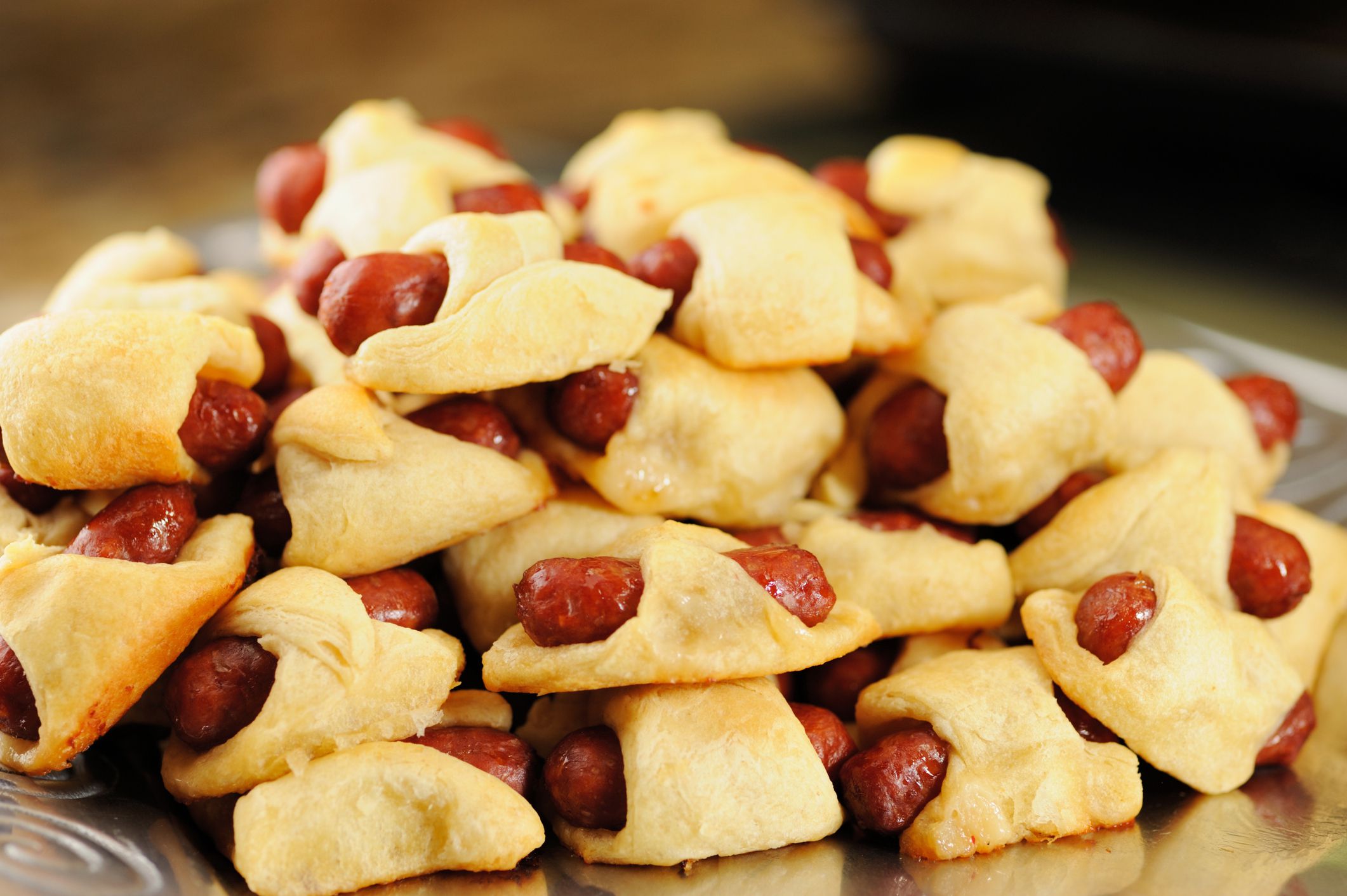 Close up pile of pigs in a blanket sausage rolls, horizontal.