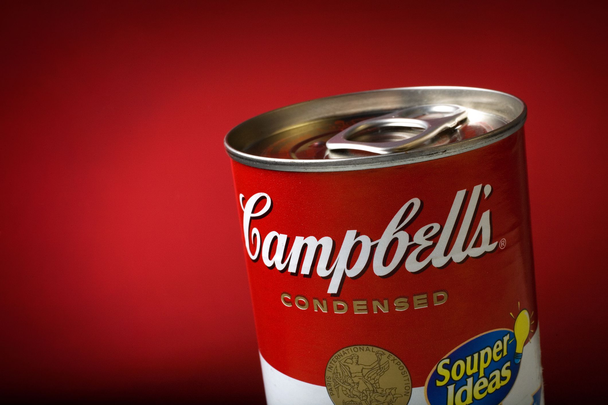 A close-up of a Campbell’s condensed soup can with a pull-tab lid, featuring the red and white label against a red background. The words “Souper Ideas” appear on a sticker on the can.