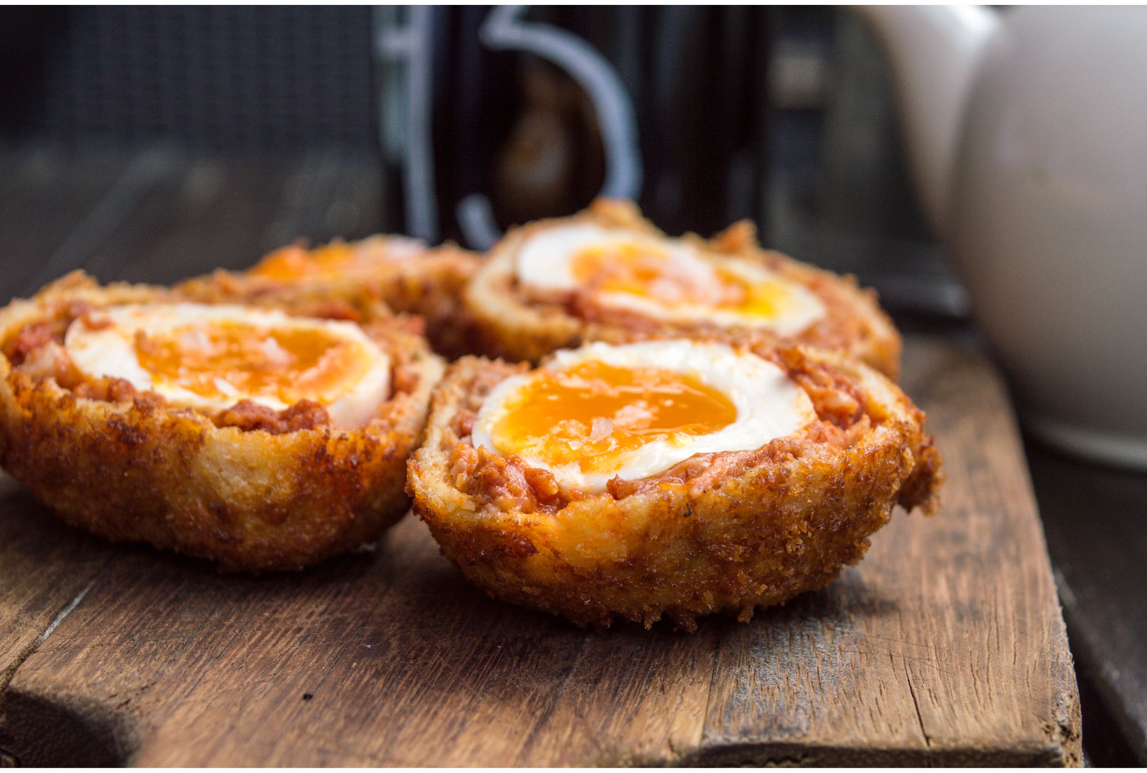 Two scotch eggs on a wooden board