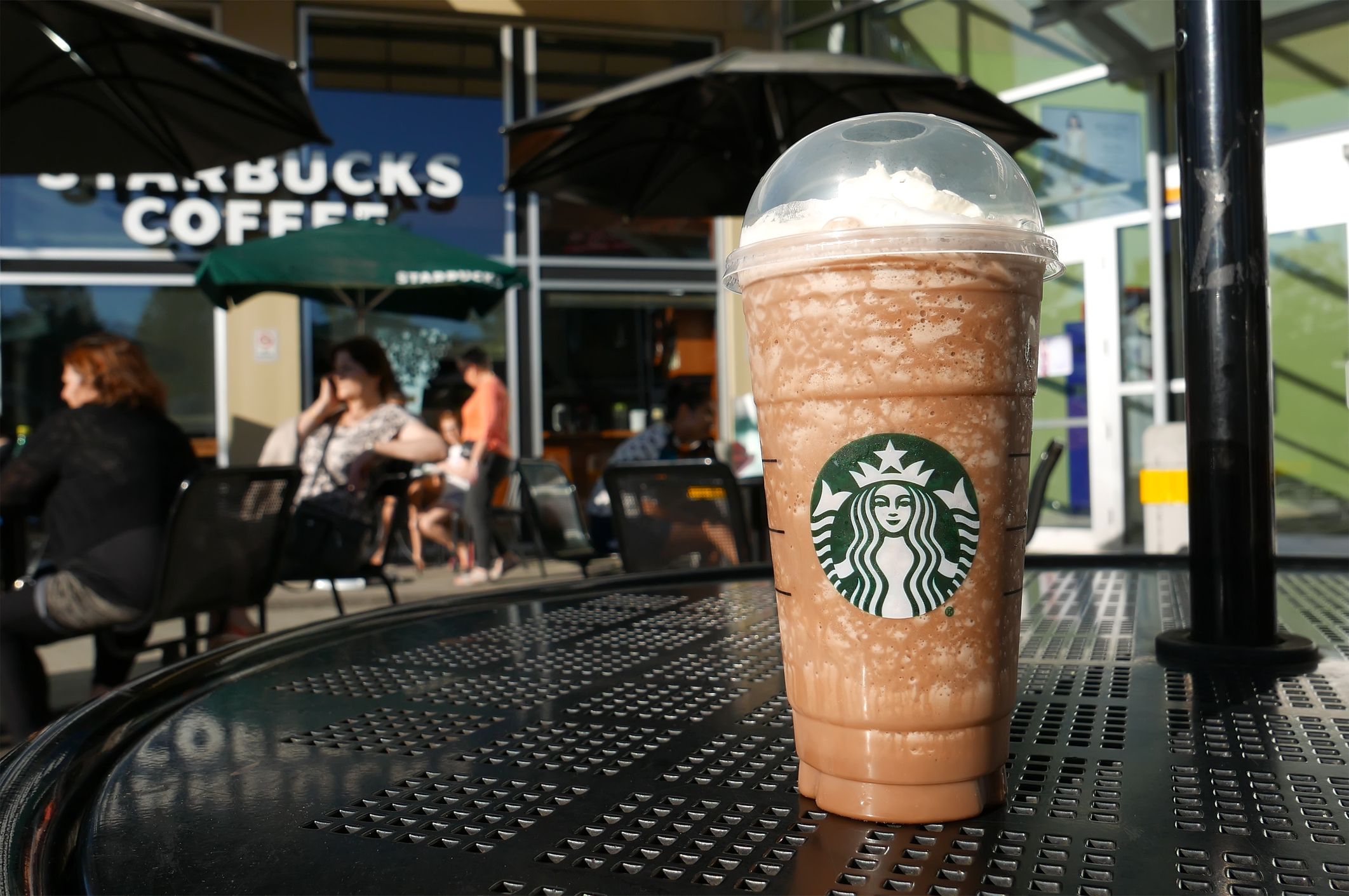 Coquitlam, BC, Canada - April 30, 2016 : One side of people drinking Starbucks coffee on sunny day. Starbucks is the largest coffeehouse company in the world.