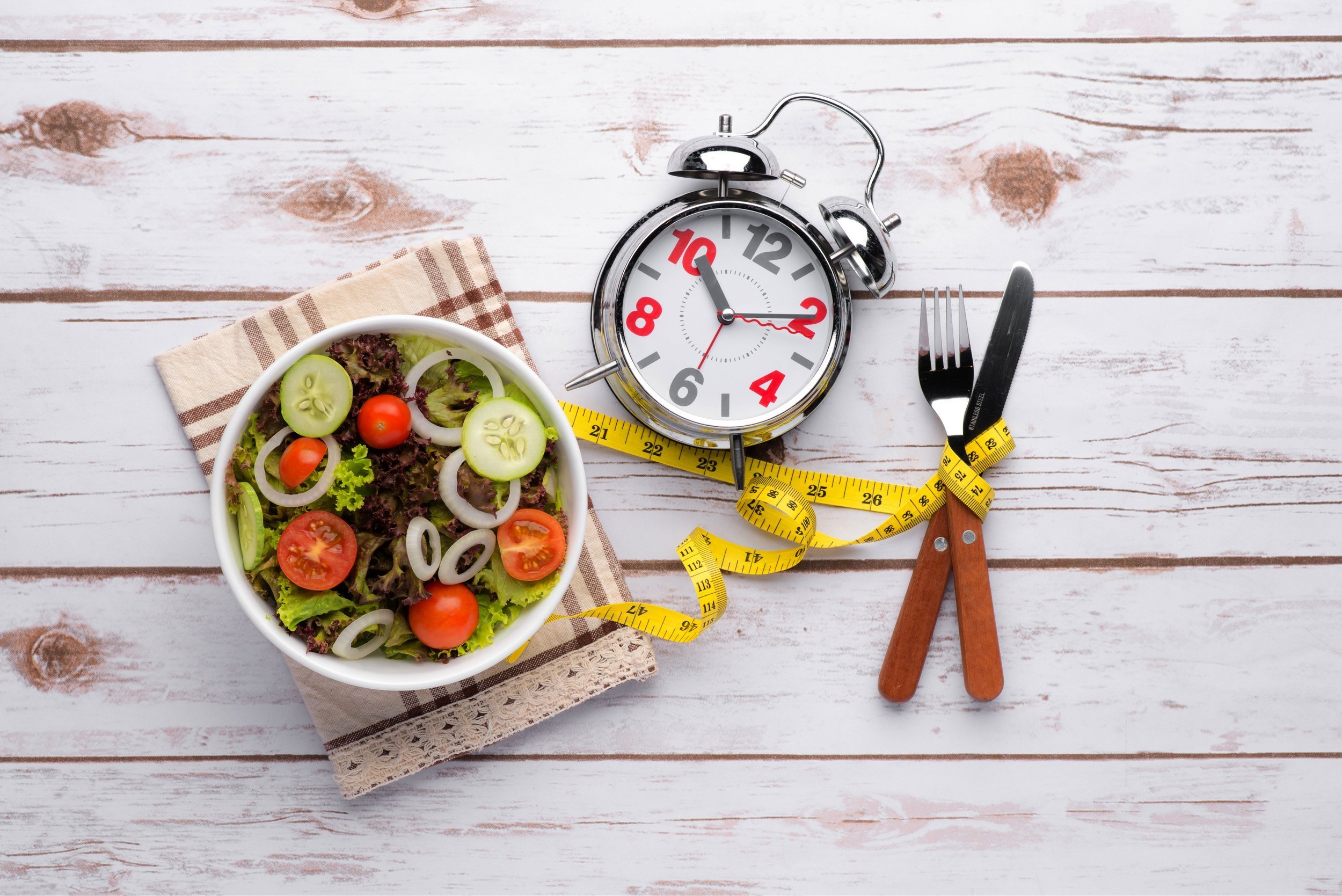Healthy salad and alarm clock isolated on white background.