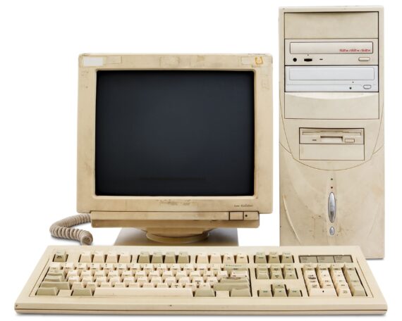 A vintage desktop computer system consisting of a beige CRT monitor, a tower case with two optical drives and a floppy drive, and a matching mechanical keyboard.