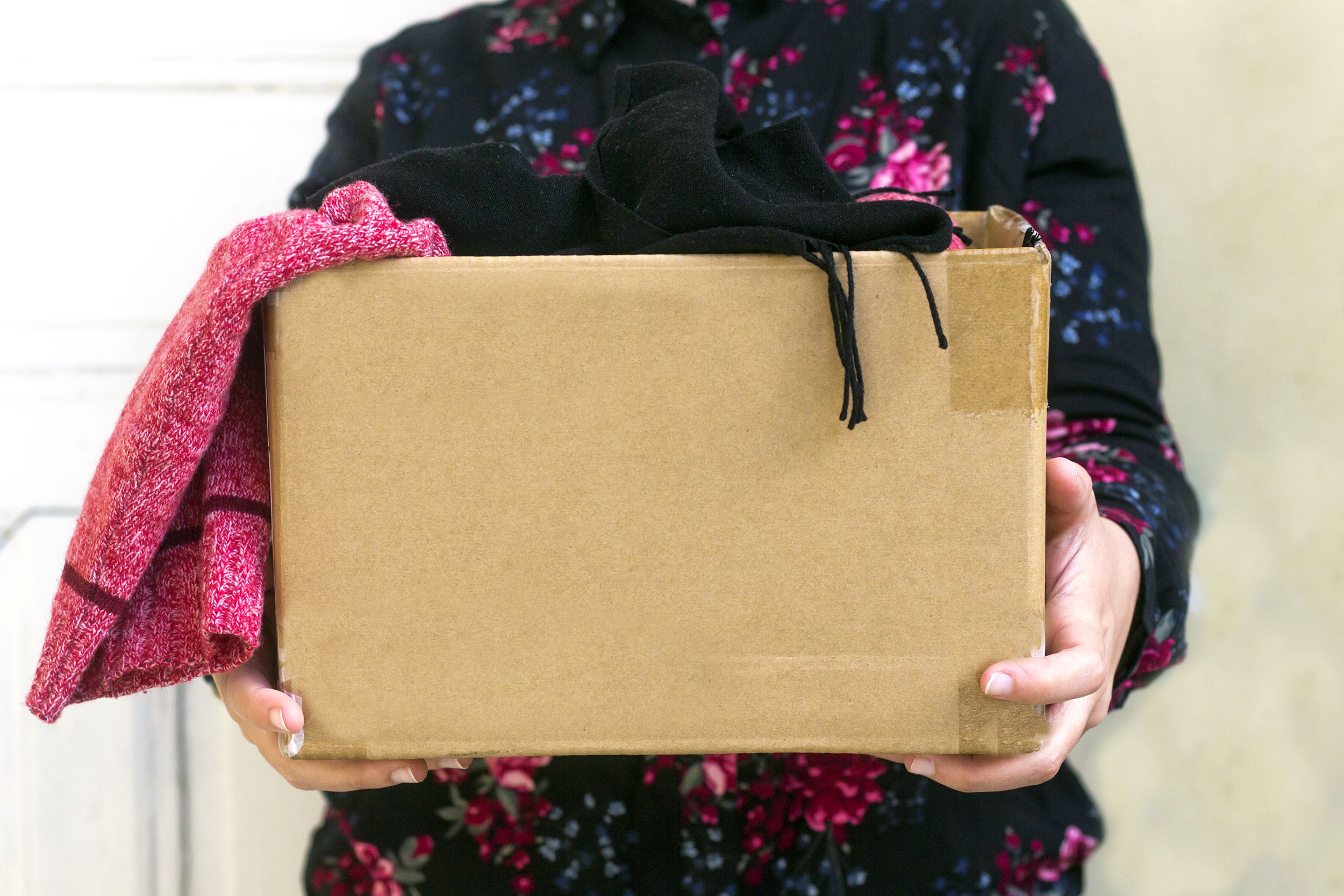 woman holding cardboard box with clothing during clothing drive