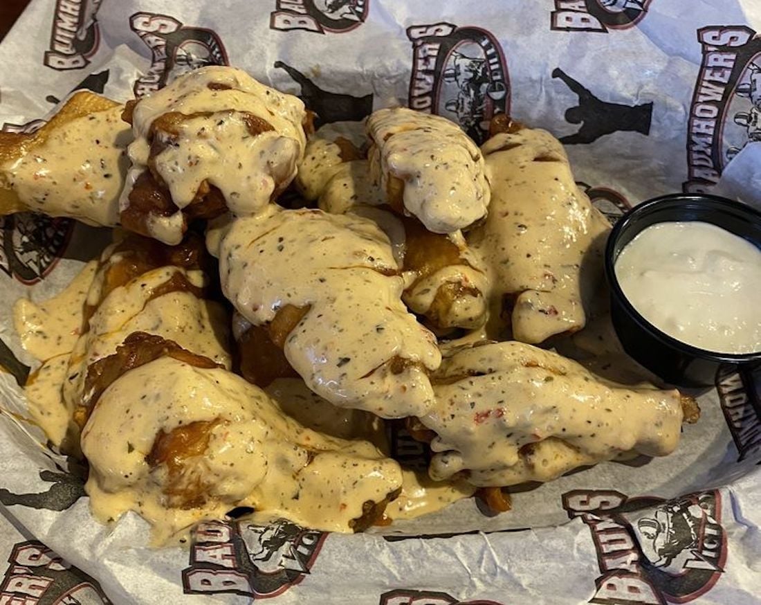 Enjoy a basket of the best chicken wings, fried to perfection and covered in creamy, pepper-speckled sauce, served on branded paper with a side of ranch or blue cheese dressing.