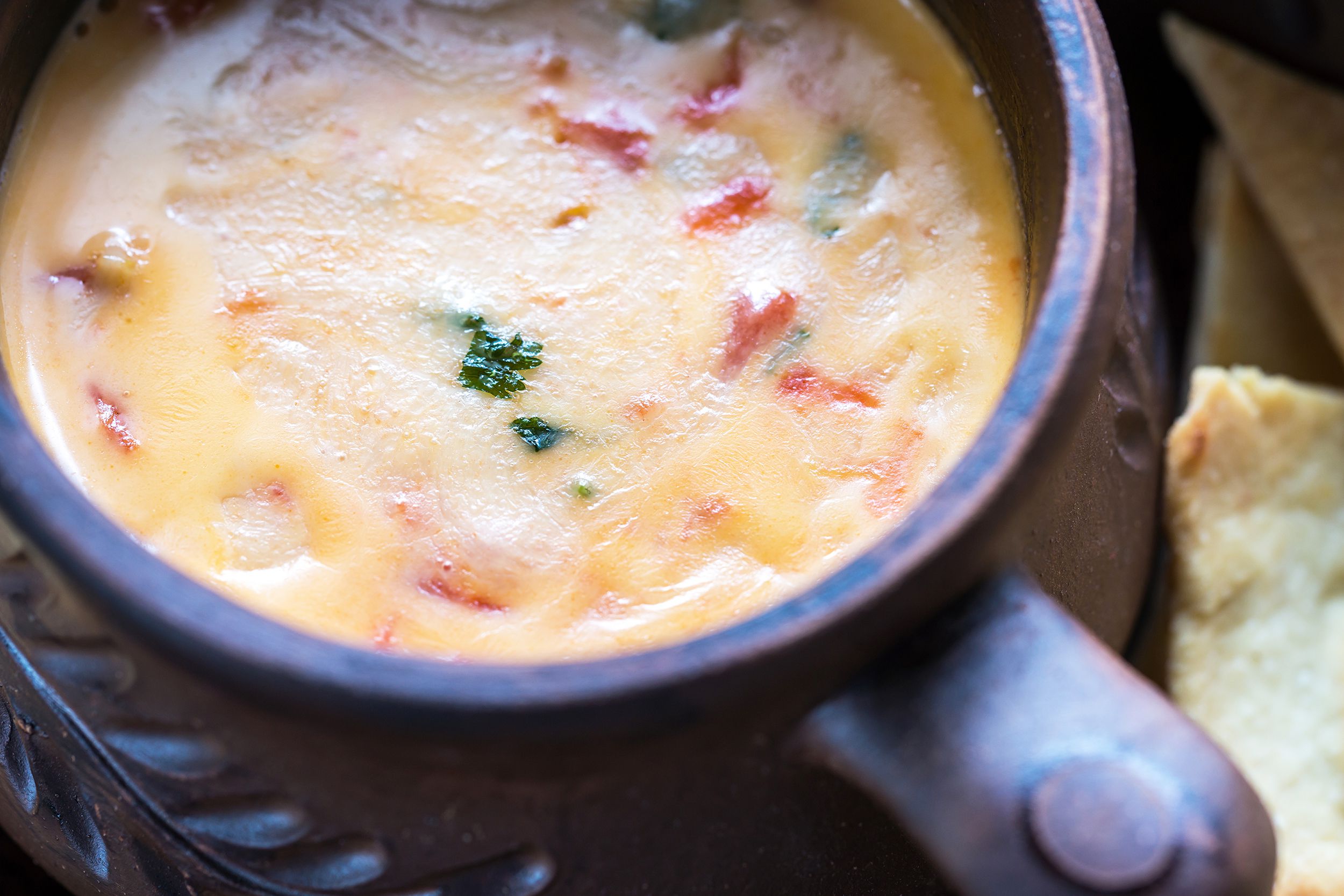 Closeup of queso fundido recipe with chorizo (crock pot queso) in a iron mug with a blurred background