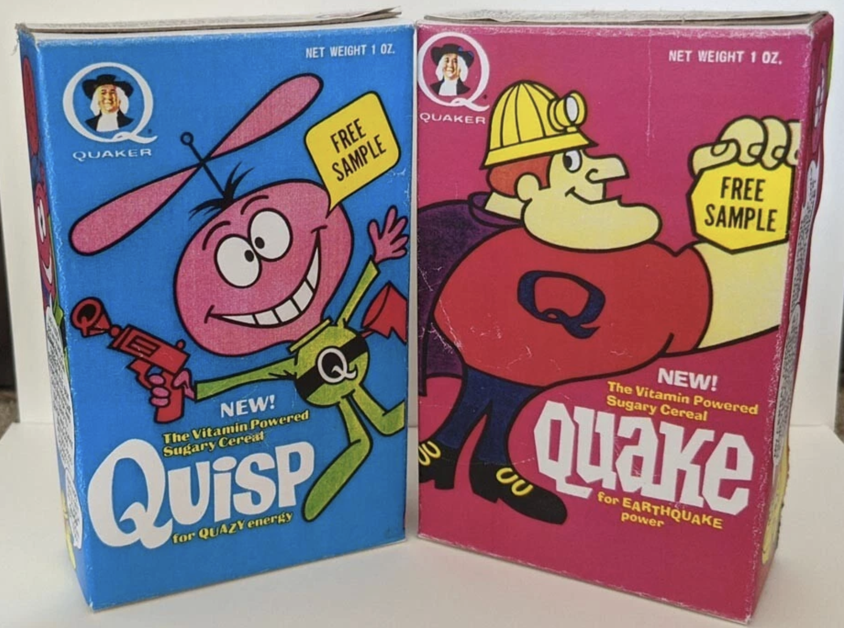 Two vintage cereal boxes: one blue box of Quisp featuring a pink cartoon alien holding a propeller gun, and one red box of Quake featuring a muscular superhero in red with a yellow cape. Both are labeled “FREE SAMPLE.”