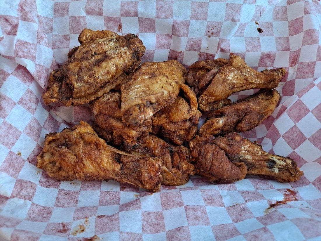 A basket lined with red and white checkered paper holds several seasoned, cooked chicken wings—perfect for anyone craving the best chicken wings around.
