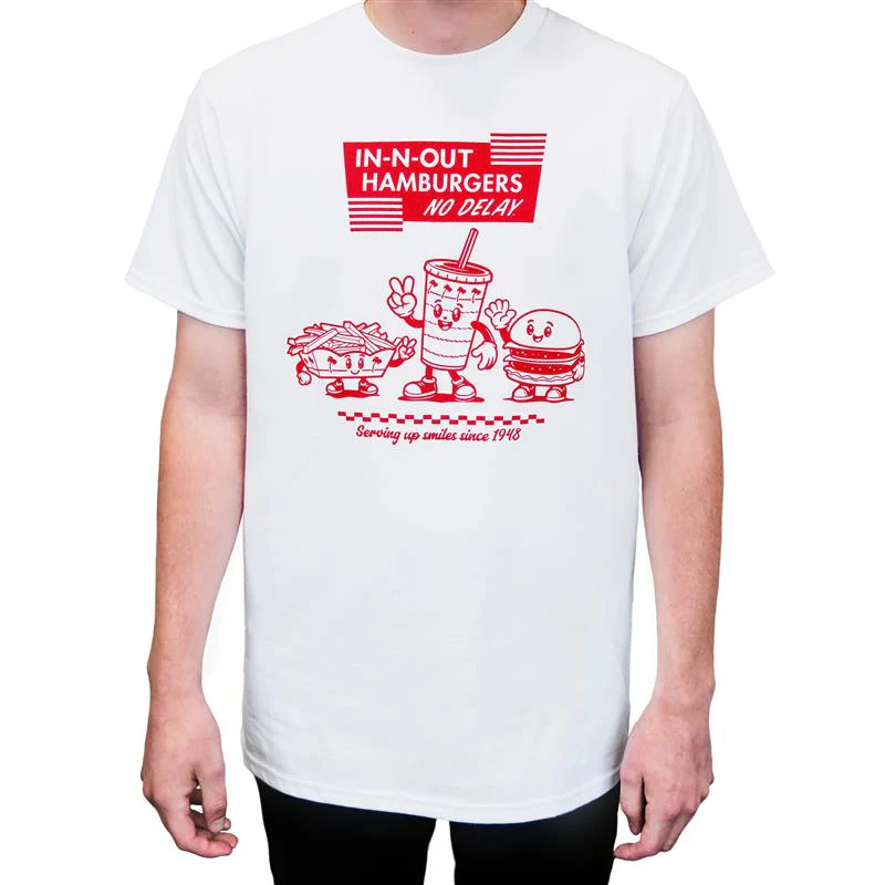 A person wearing a white T-shirt with red cartoon graphics of fries, a drink, and a hamburger. The shirt reads "IN-N-OUT HAMBURGERS NO DELAY" and "Serving up smiles since 1948.