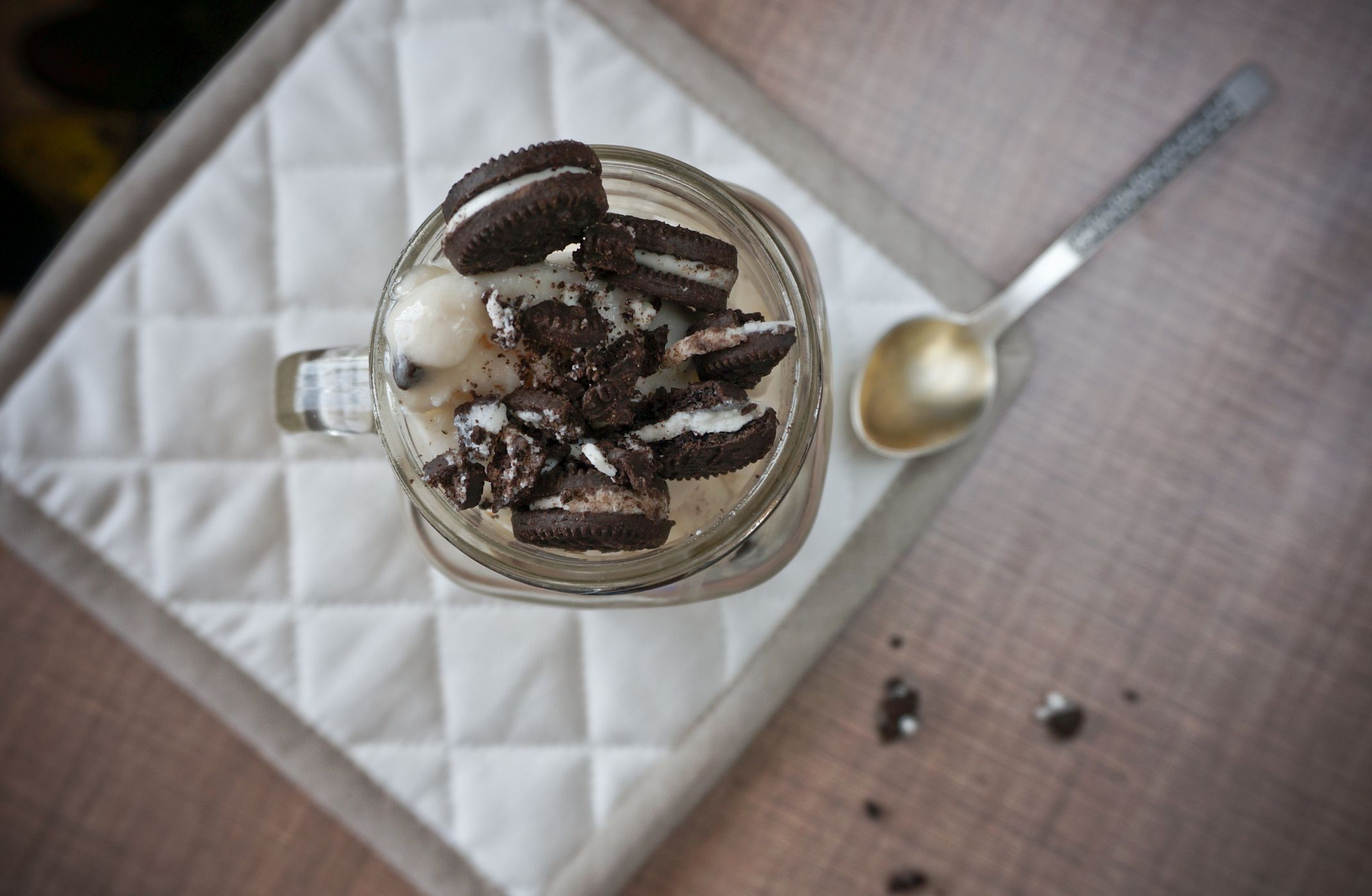 Almond vegan ice-cream in mason jar topped with chocolate cookies on dark background