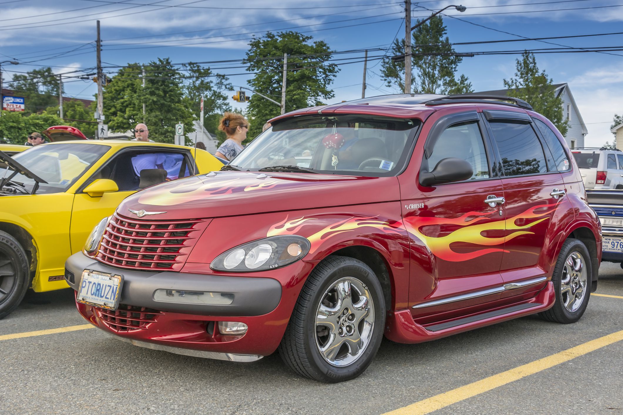 Dartmouth, Nova Scotia, Canada - July 30, 2015: Chrysler PT Cruiser with a custom flamed paint job participates at weekly summer cruise-in. People can be seen in the distance looking at the many cars on display.