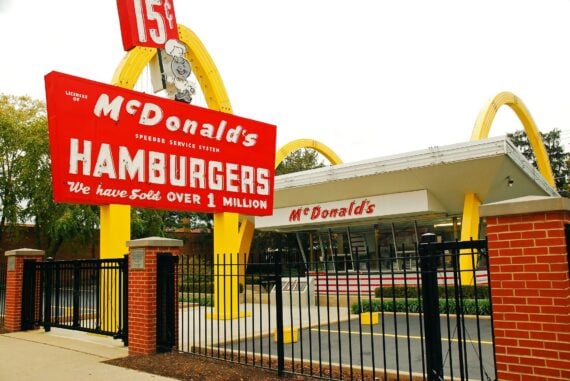 A vintage McDonald’s restaurant with its signature yellow arches and a large red sign stating “McDonald’s Hamburgers, We have sold over 1 million.”