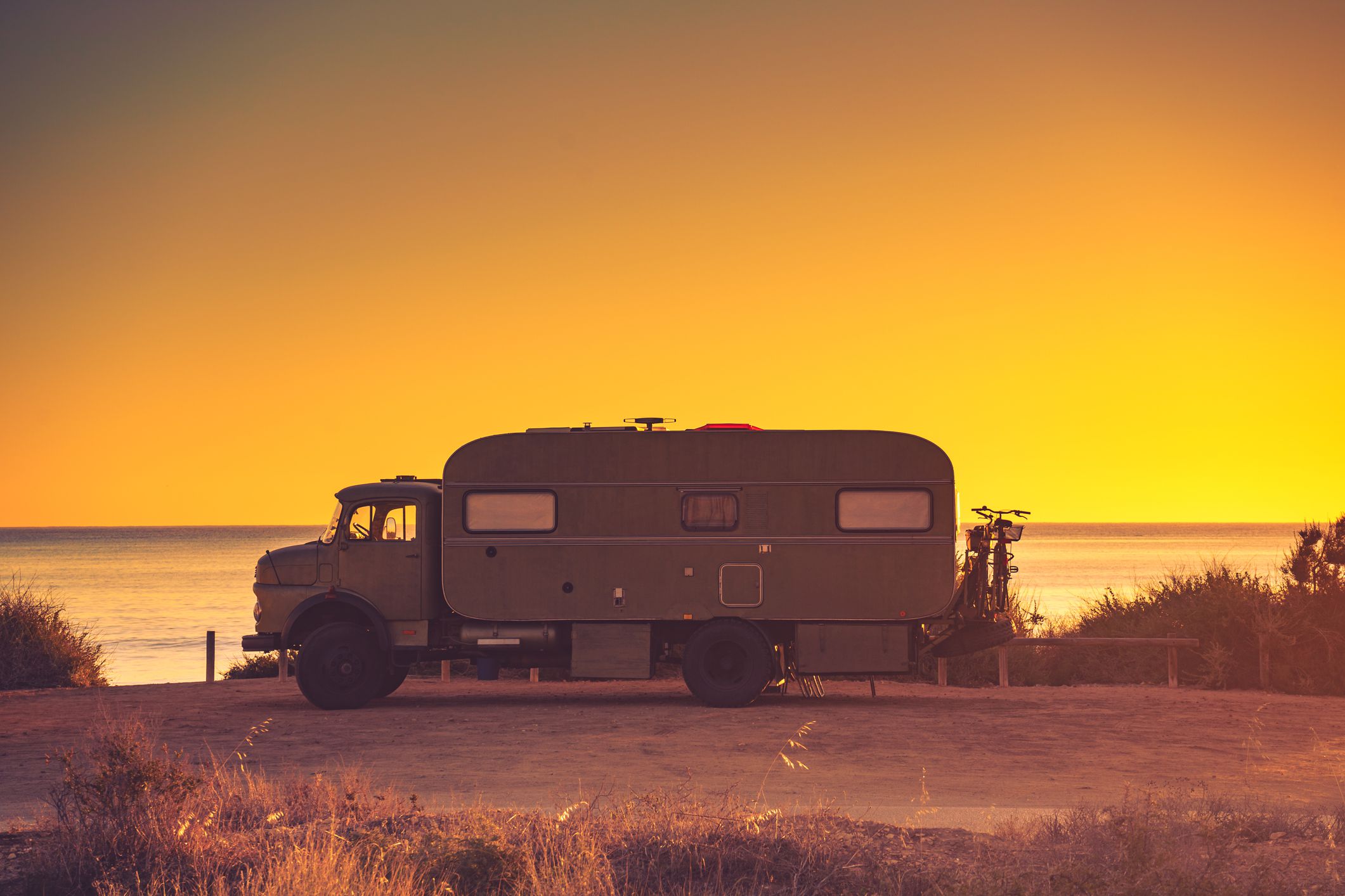 Camper recreational vehicle at sunset on mediterranean coast in Spain. Camping on nature beach. Holidays and travel in motor home.