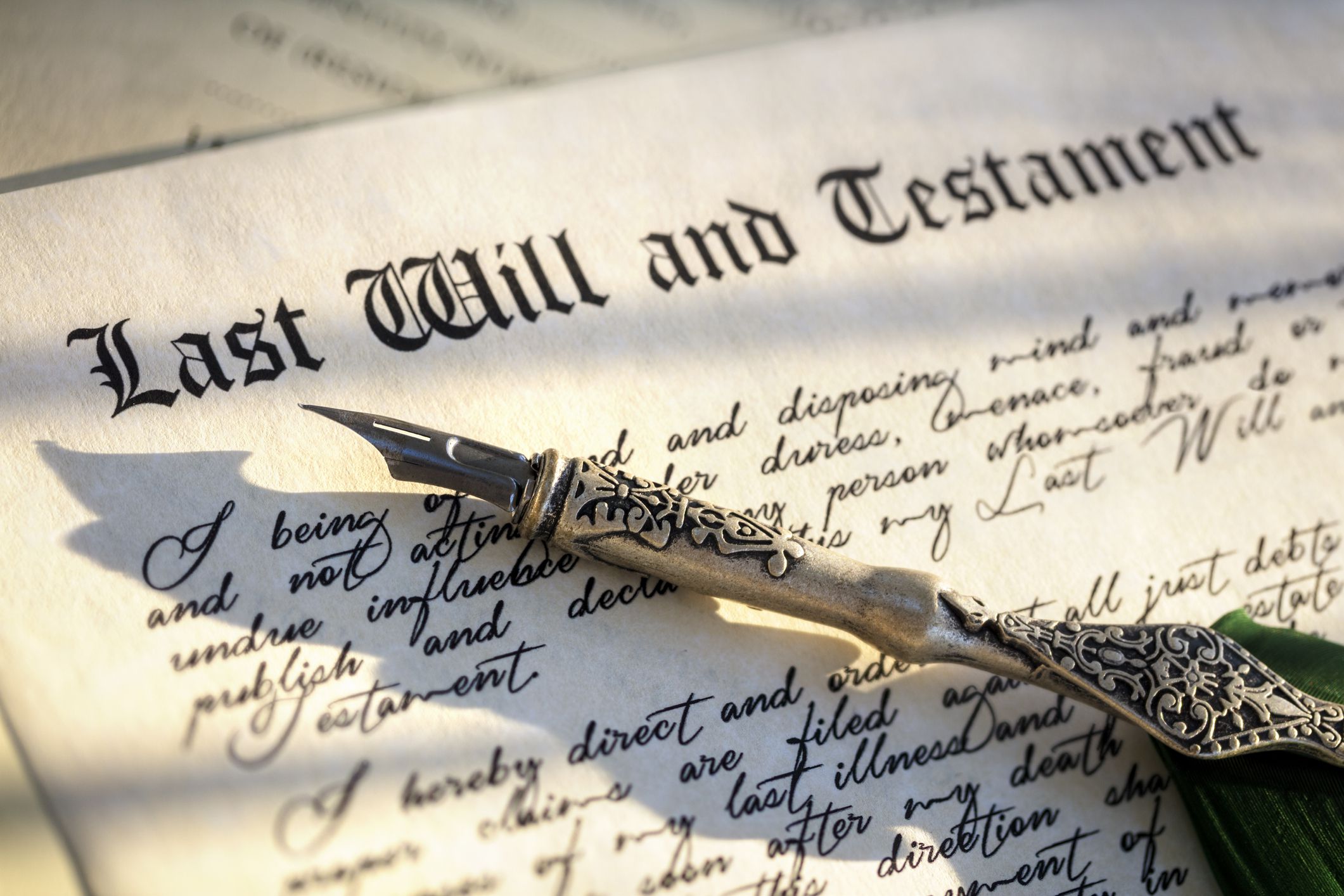 Signing Last Will and Testament legal document with quill pen