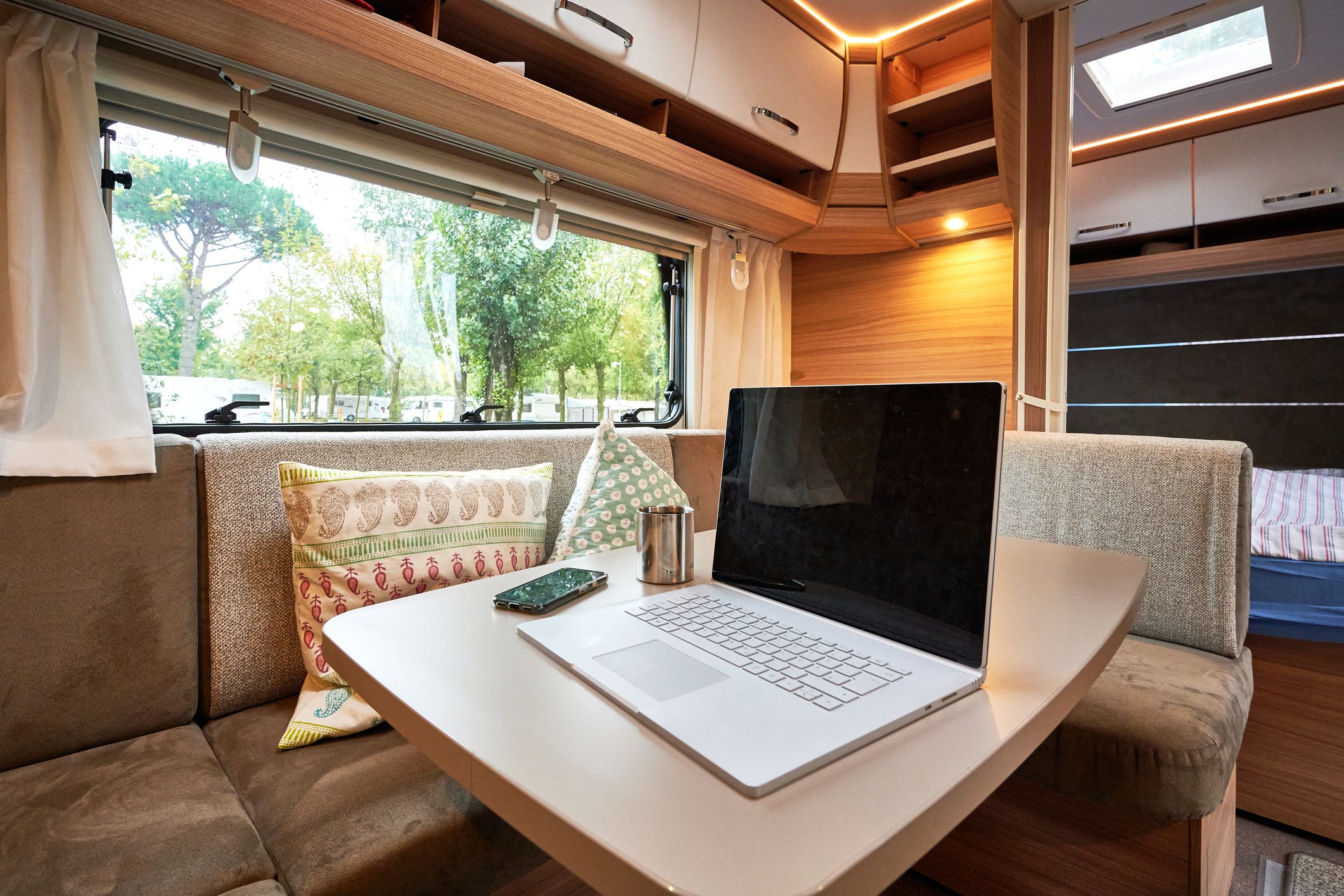 Arbeiten Mobile Work vom Urlaub aus auf dem Campingplatz mit einem Laptop in einem Wohnwagen Wohnmobil