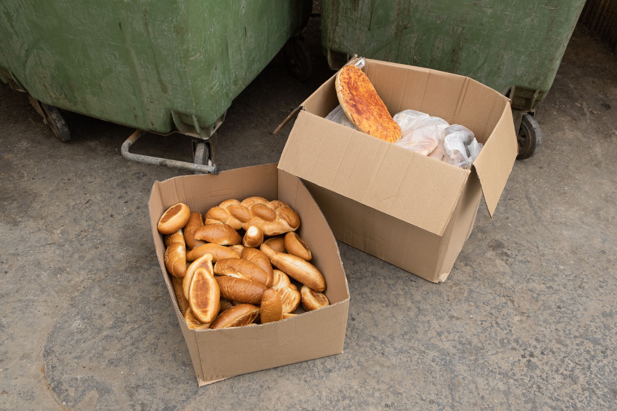 Carton box with bread in it, near a waste container in Israel. left for homeless and hungry people in the city.