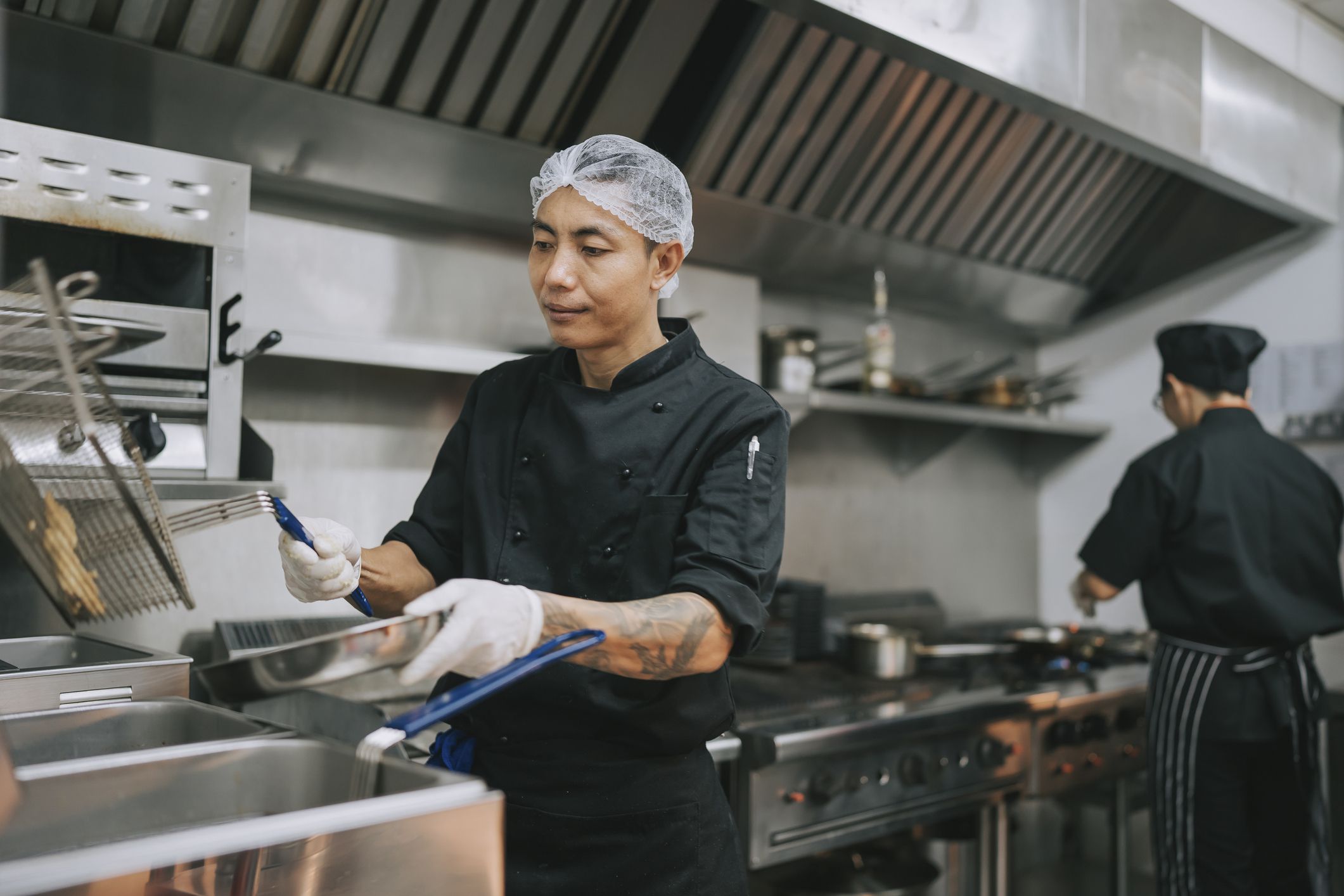 Asian Kitchen crew dripping dry fried french fries from appliance