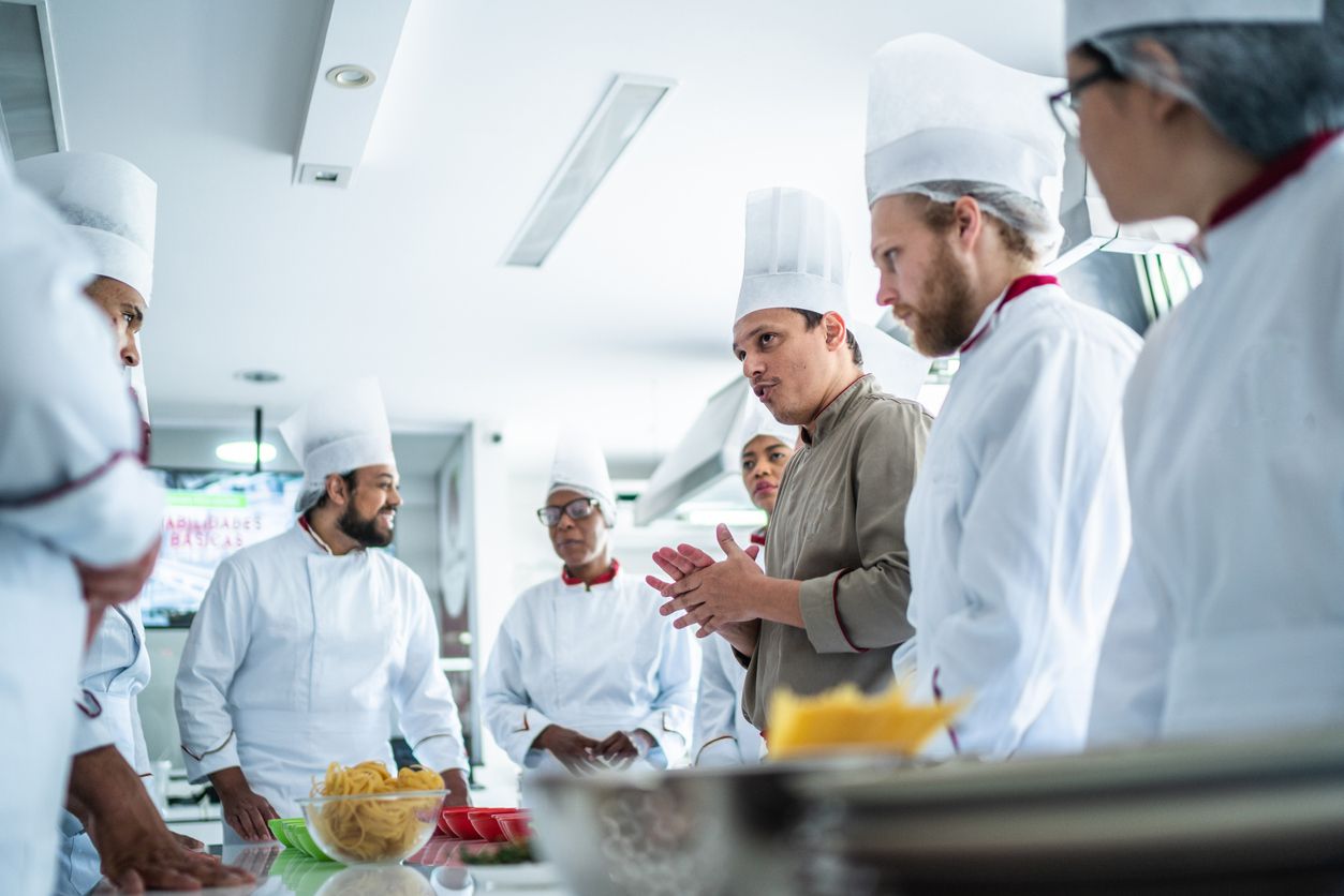A bunch of kitchen staff strategizing in kitchen.