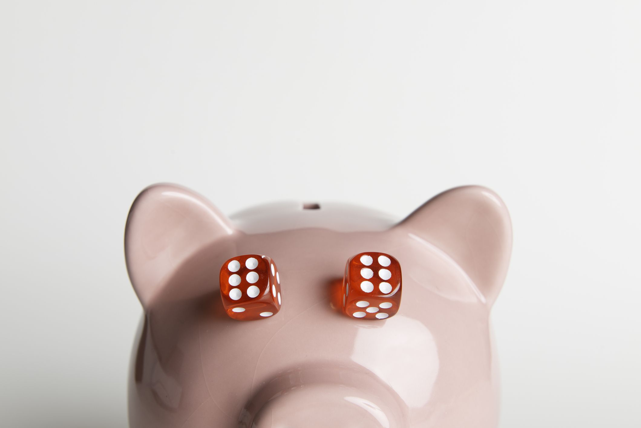 Two red dices on piggy banks eyes. Representing luck in gambling.