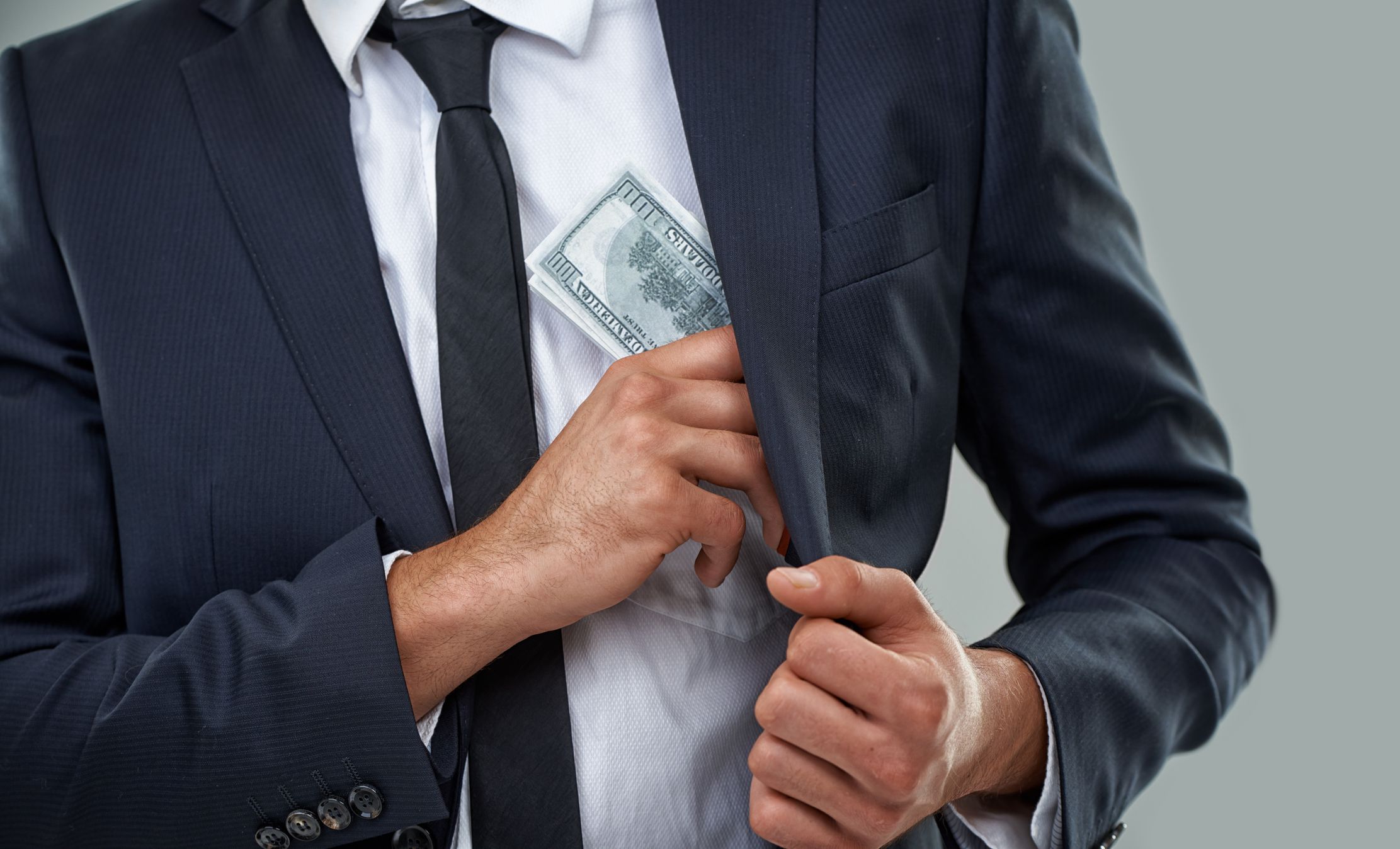 Man in suit putting money in pocket