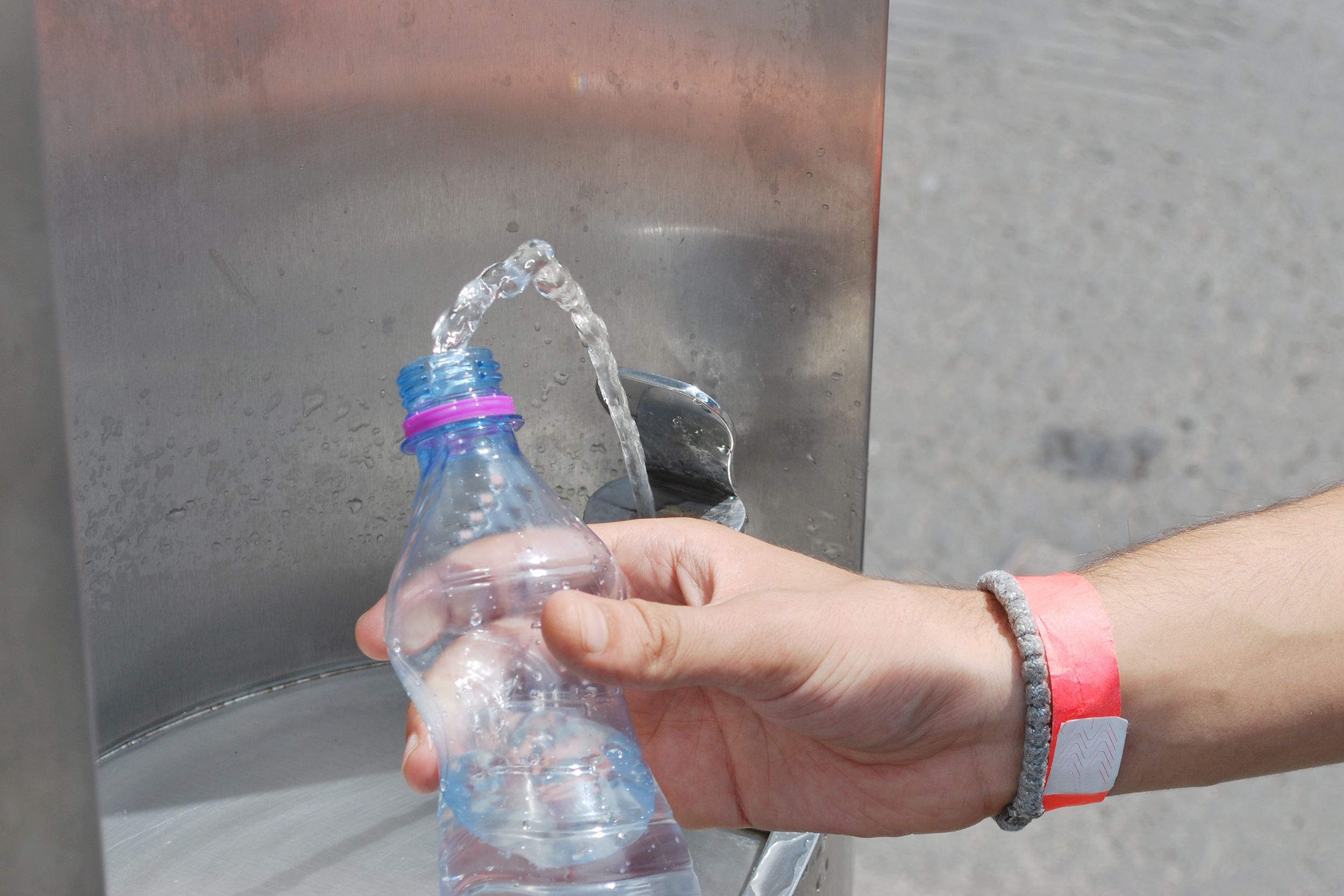 person refilling water bottle at water fountain