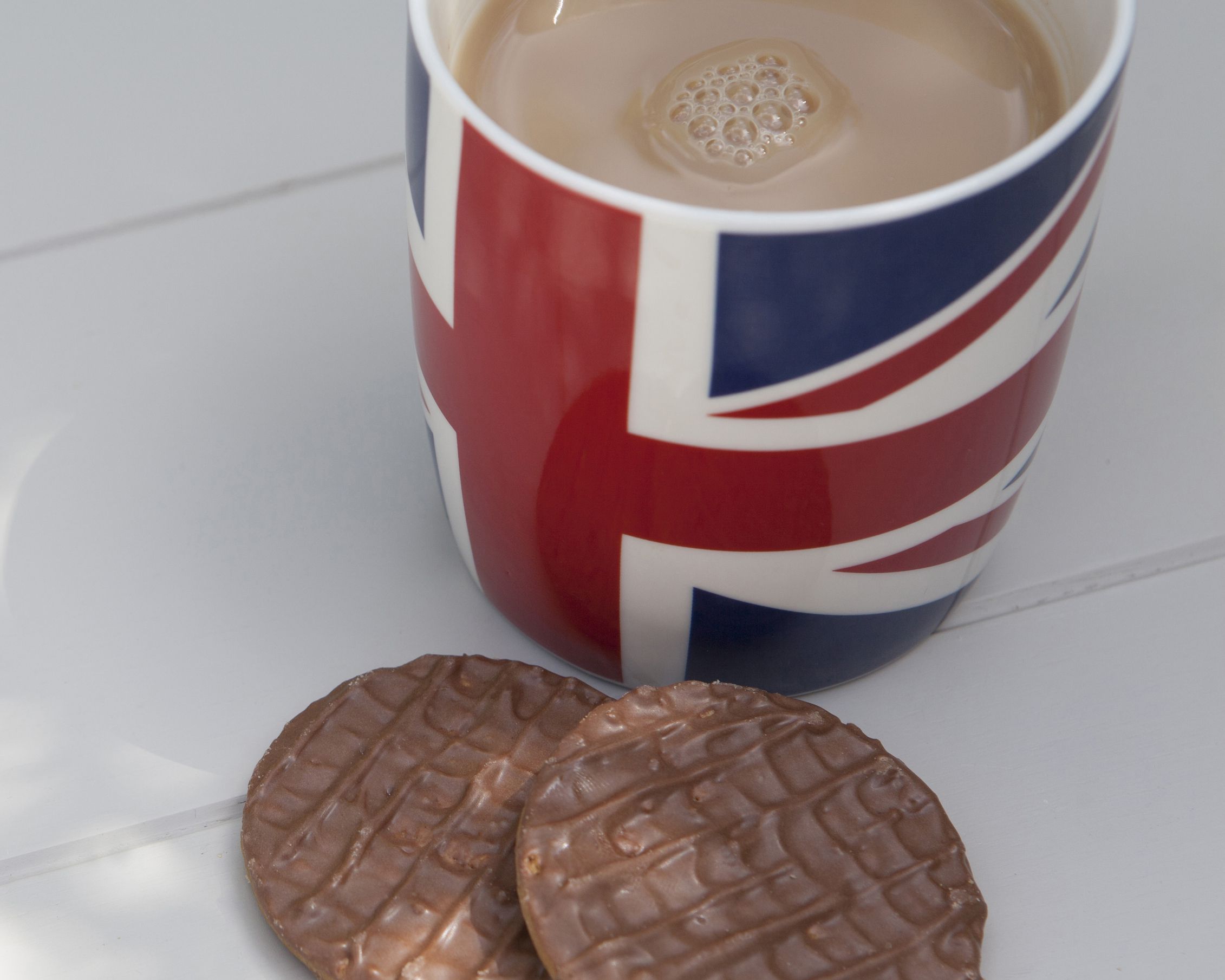 British tea in Union Jack mug and chocolate covered biscuits on wooden background