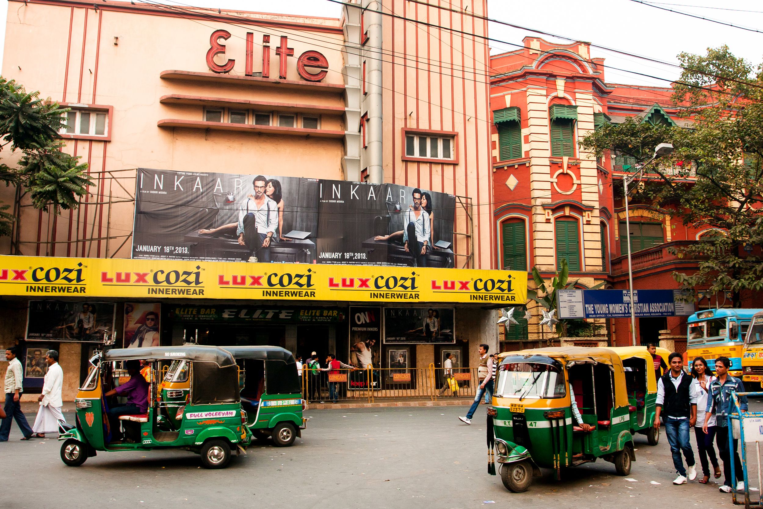 Auto rickshaw taxis and pedestrians move past the old cinema theater on January 19, 2013, Kolkata, India