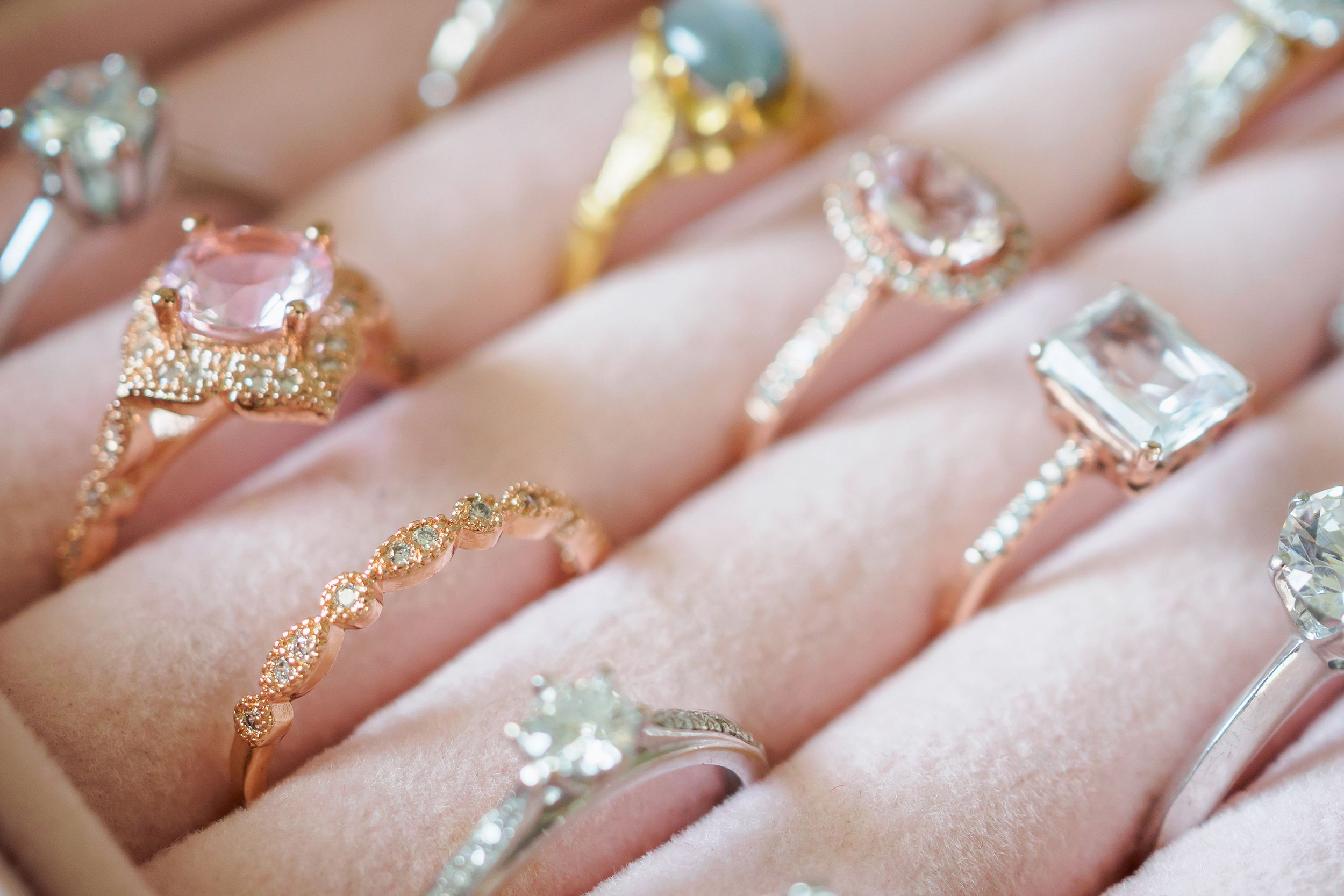 Closeup of several rings in a pink ring box, gold, diamonds, and platinum, with a blur on the top corner
