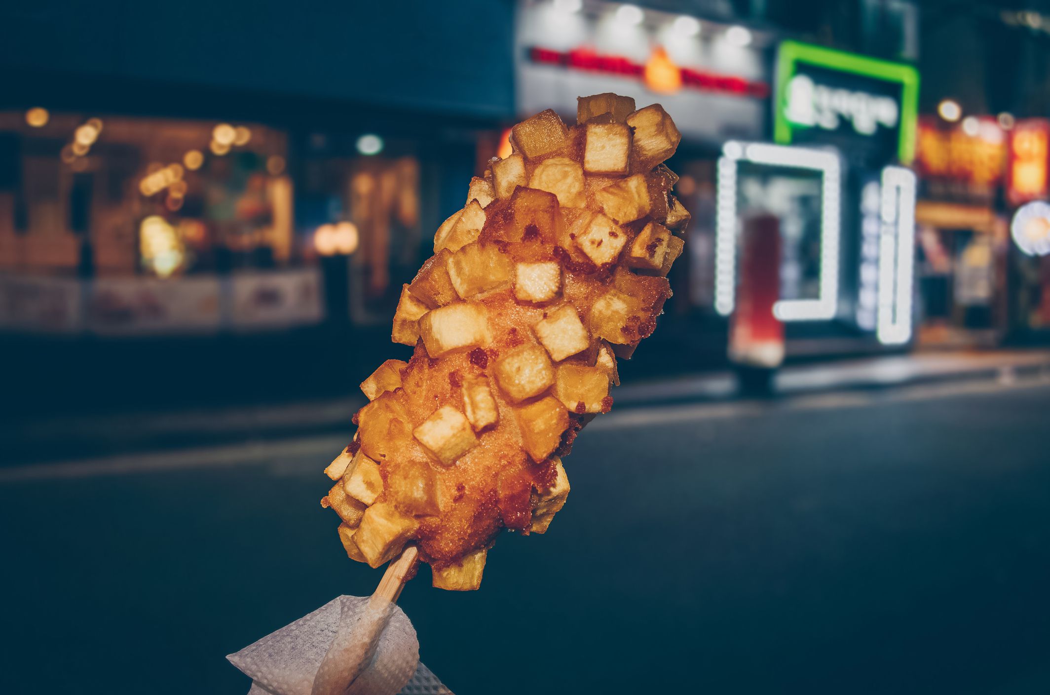 Korean corn dog made with fried potatoes with blurred night cityscape on background - stock photo