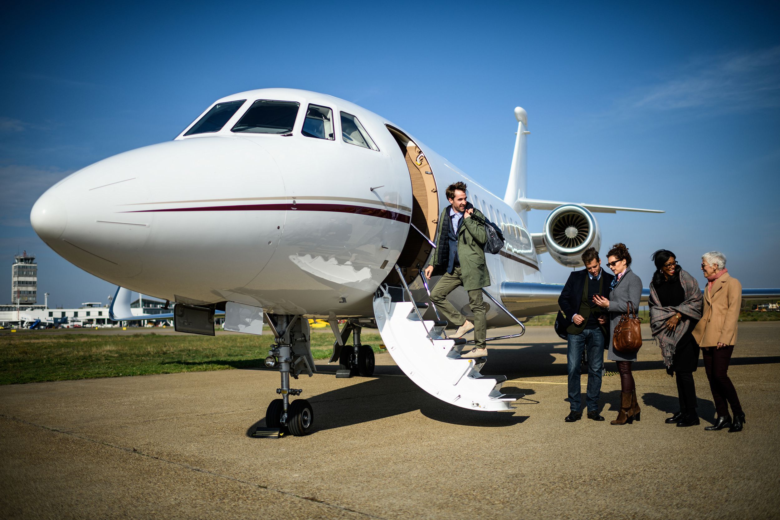 Mixed group of people boarding private airplane on runway