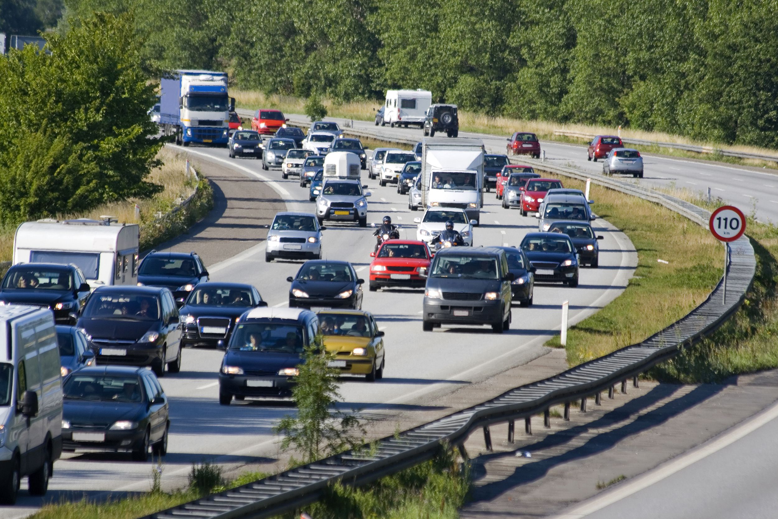 Rush hour traffic on a highway in Denmark during summer, highway on left is congested but moving, while side on right ha a few cars and moving normally