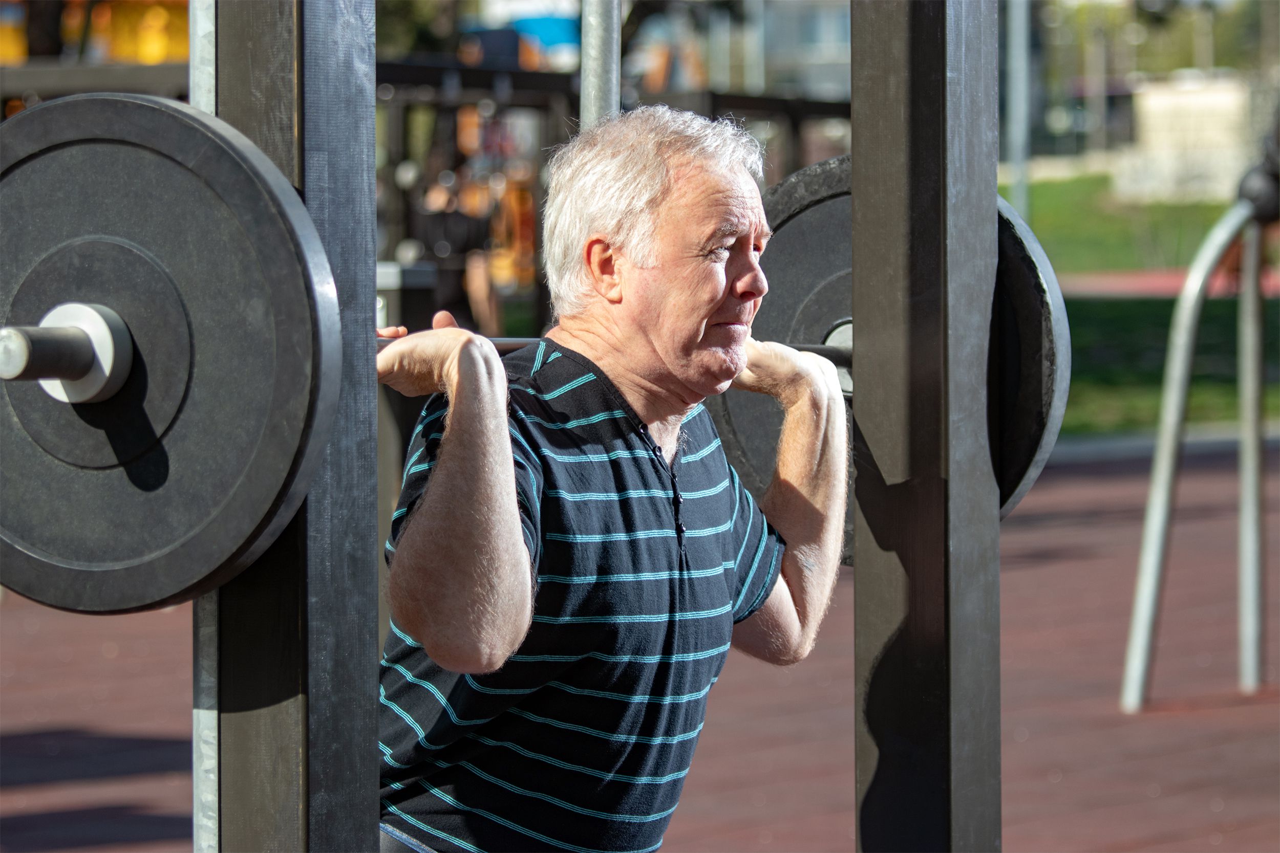 Senior man doing squats with weights