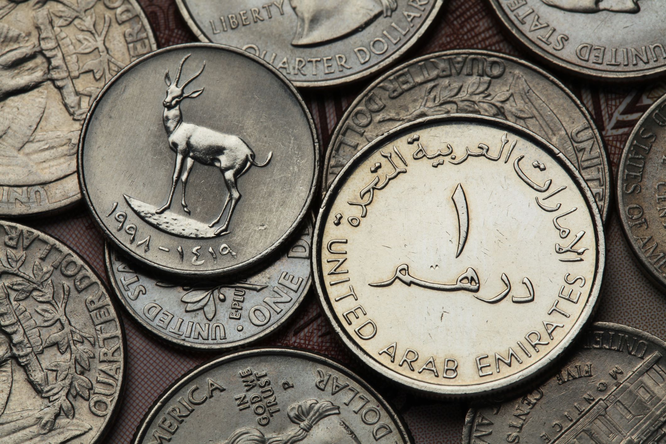 Two United Arab Emirates coins against a background of USA coins