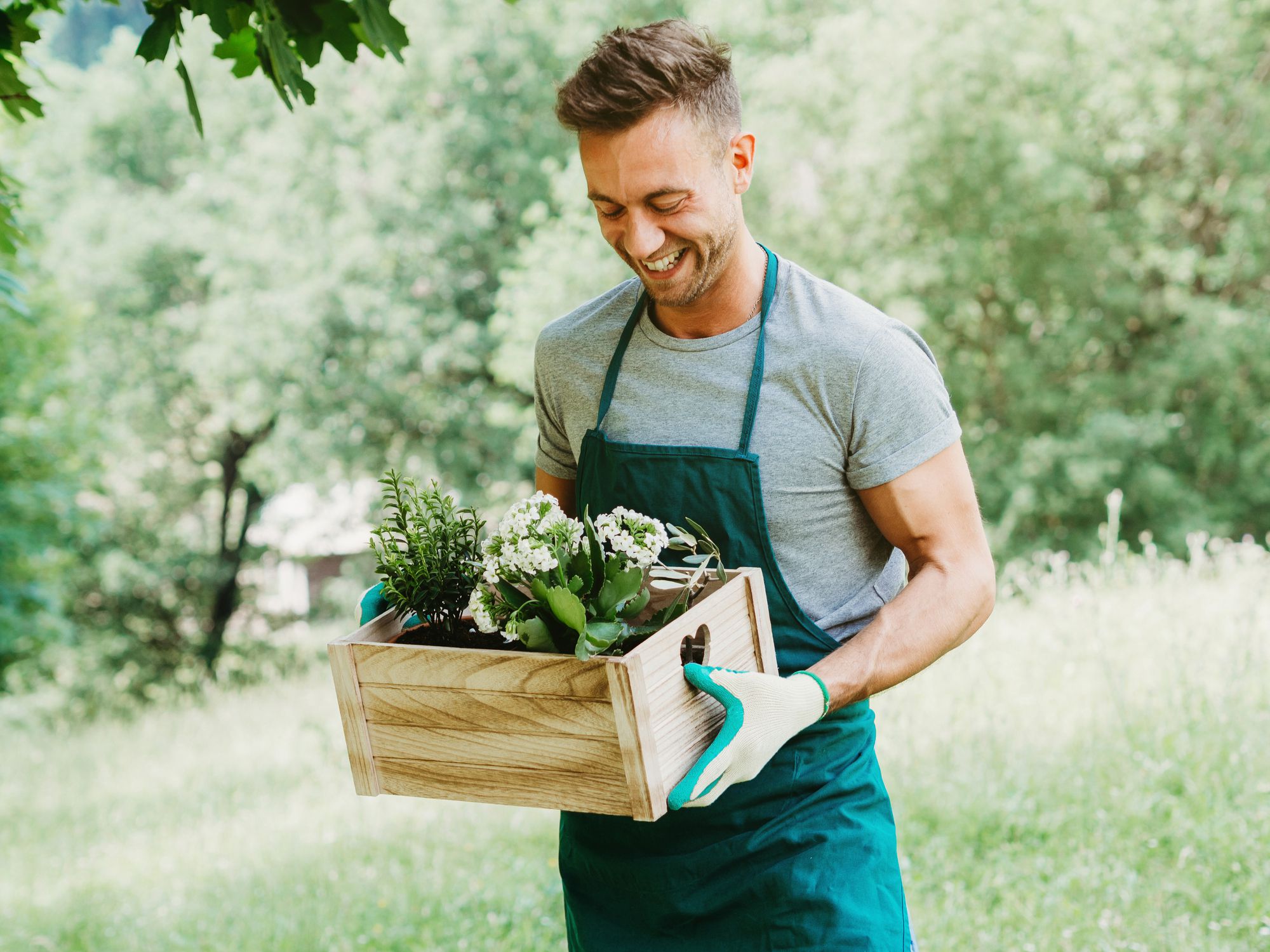 man holding box of flowers smiling in spring greenery